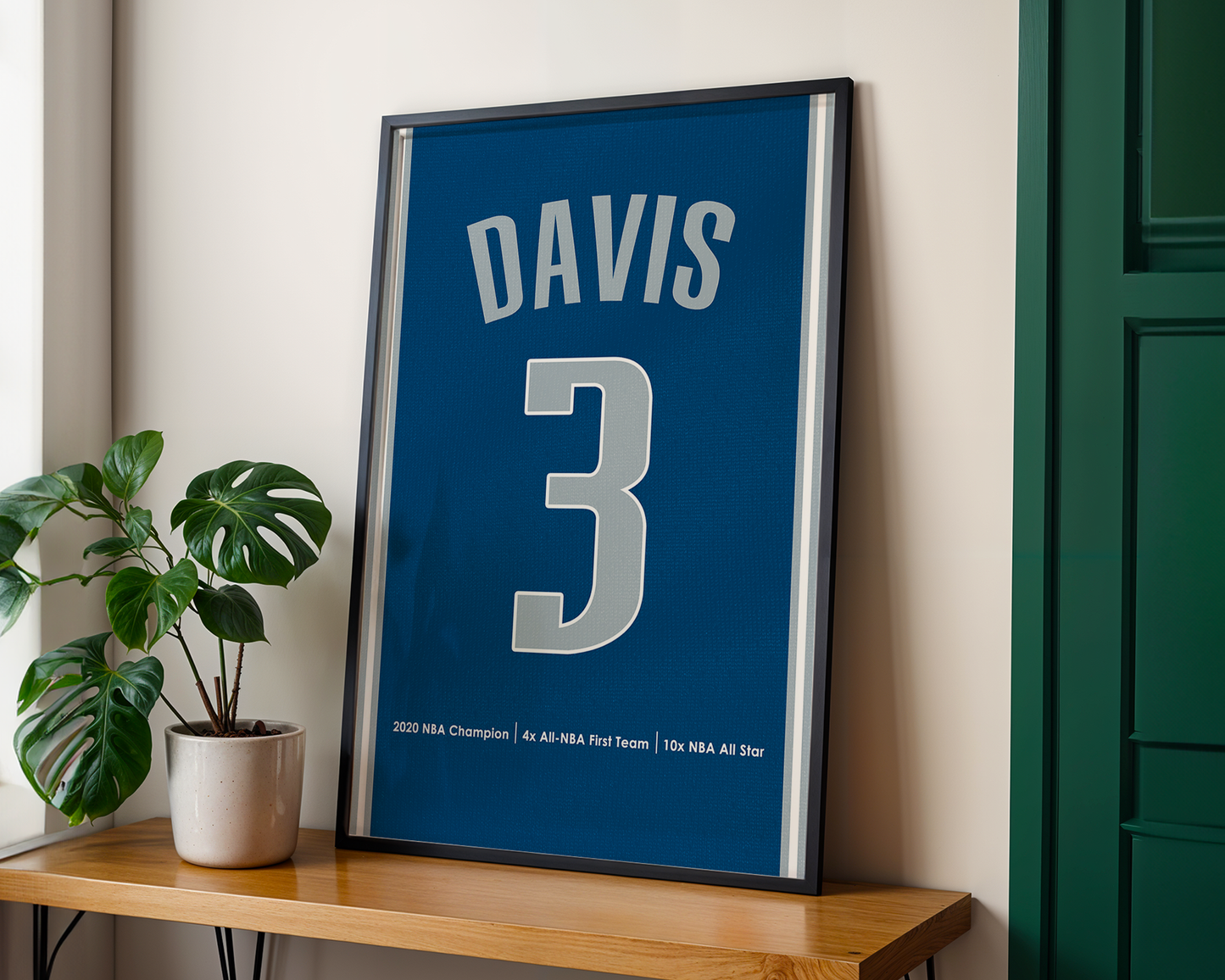 Framed sports jersey with 'DAVIS' and number '3' on a wooden shelf with a plant.