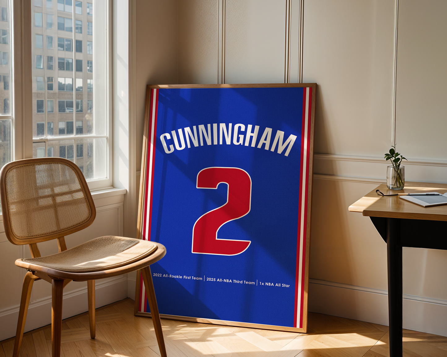 Framed sports jersey with 'Cunningham 2' on a wooden floor near a window.