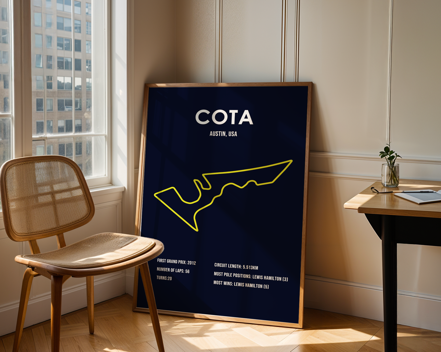 Framed poster with 'COTA' and map design in a room with a chair and window.
