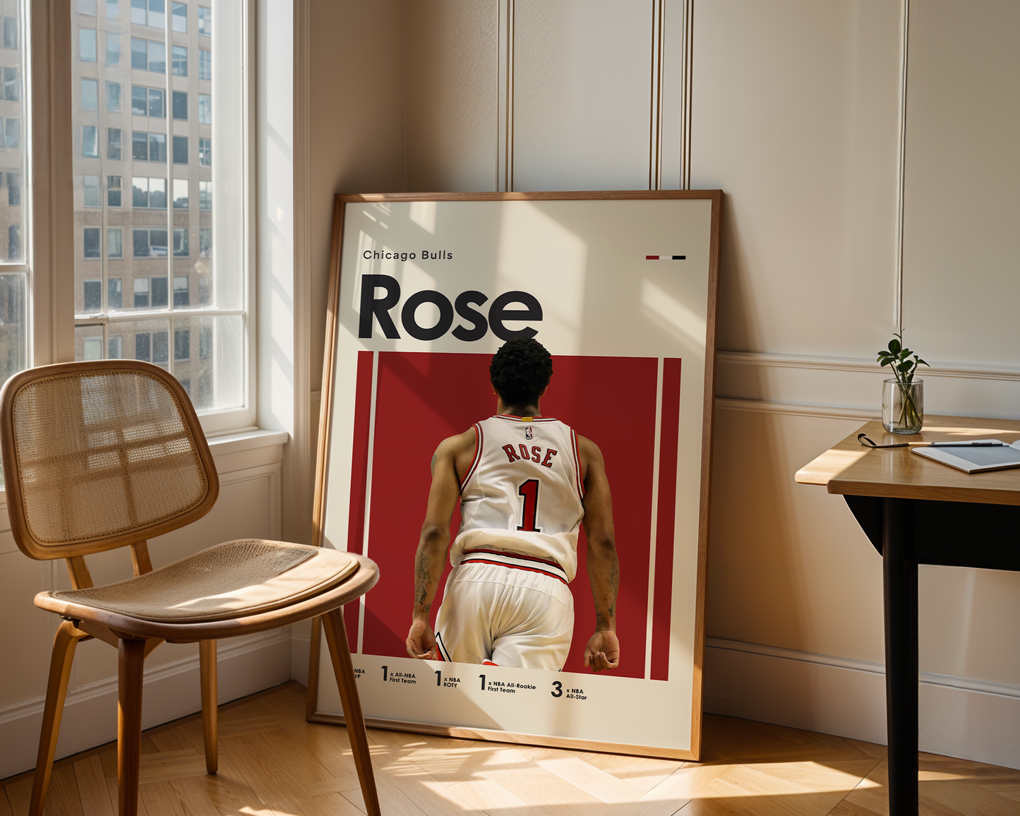 Framed poster of a basketball player with 'Rose' on a red background, leaning against a wall in a room with a chair and table.