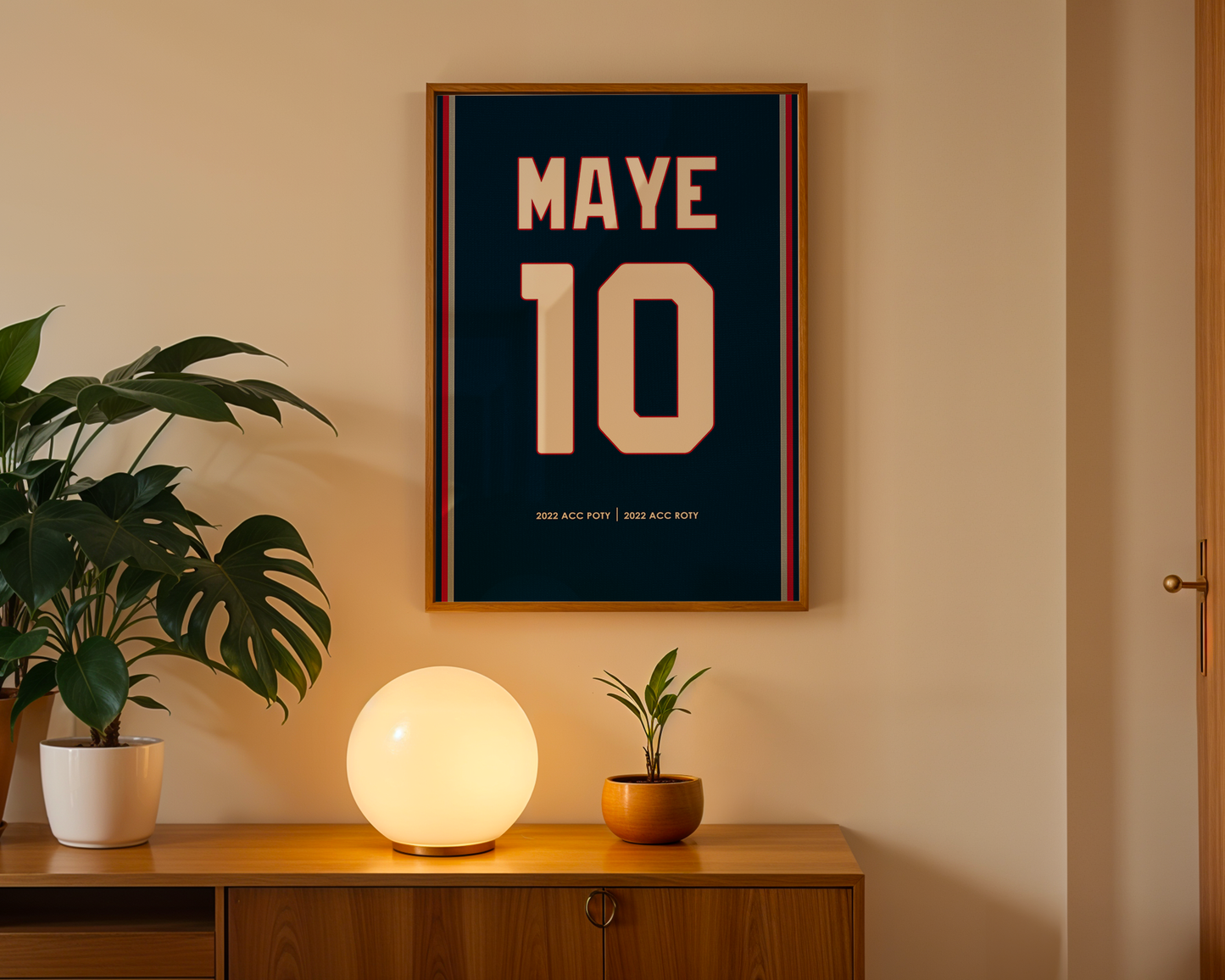 Framed poster with 'MAYE 10' on a wall above a wooden cabinet with decorative items.