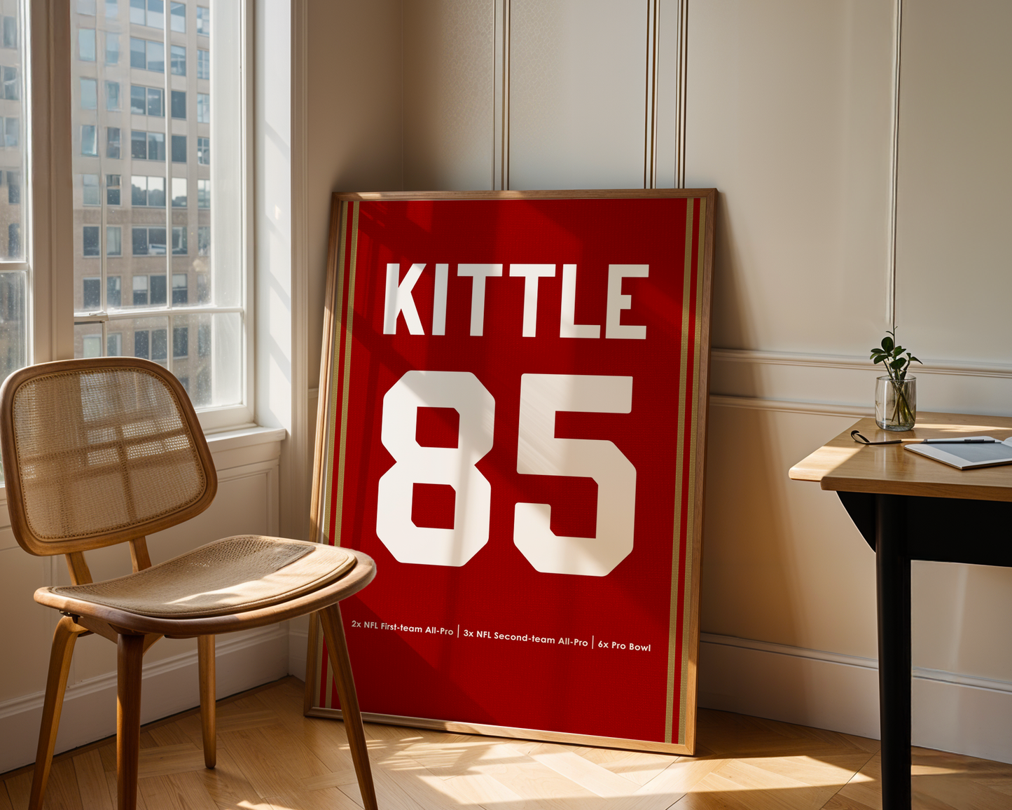 Red sports jersey with 'Kittle 85' on a wall in a room with a chair and table.