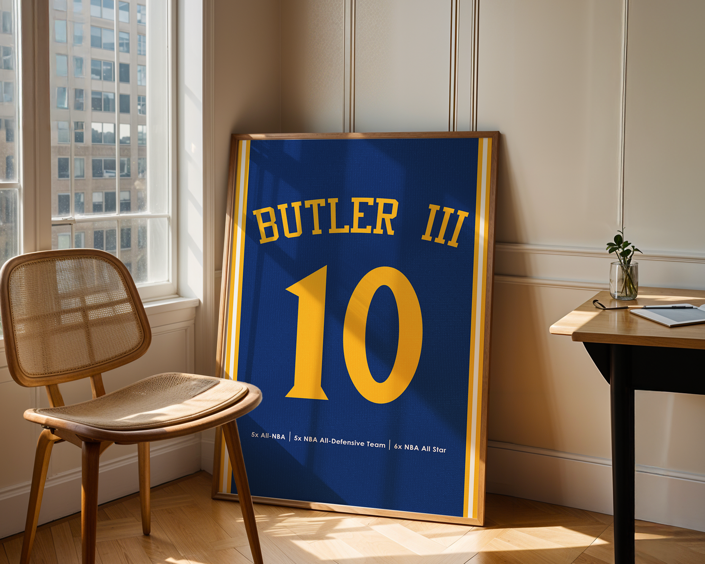 Framed sports jersey with 'Butler III' and number '10' in a room with a window and chair.