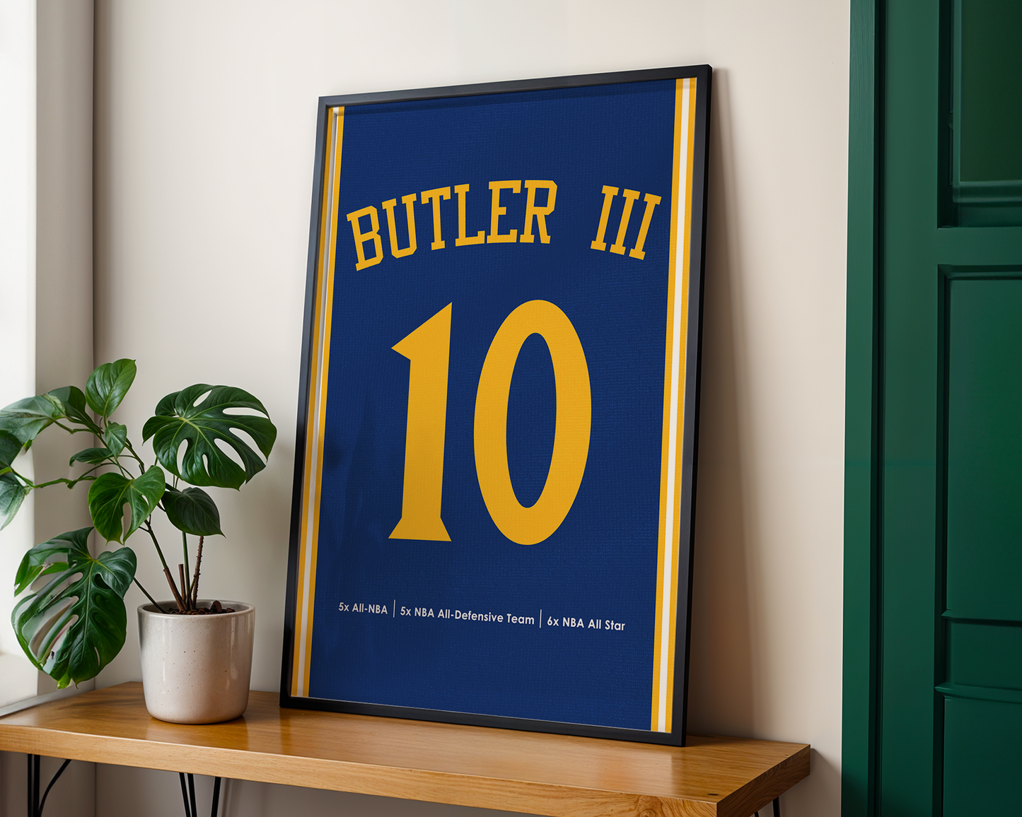 Framed sports jersey with 'Butler III' and number '10' on a wooden shelf.