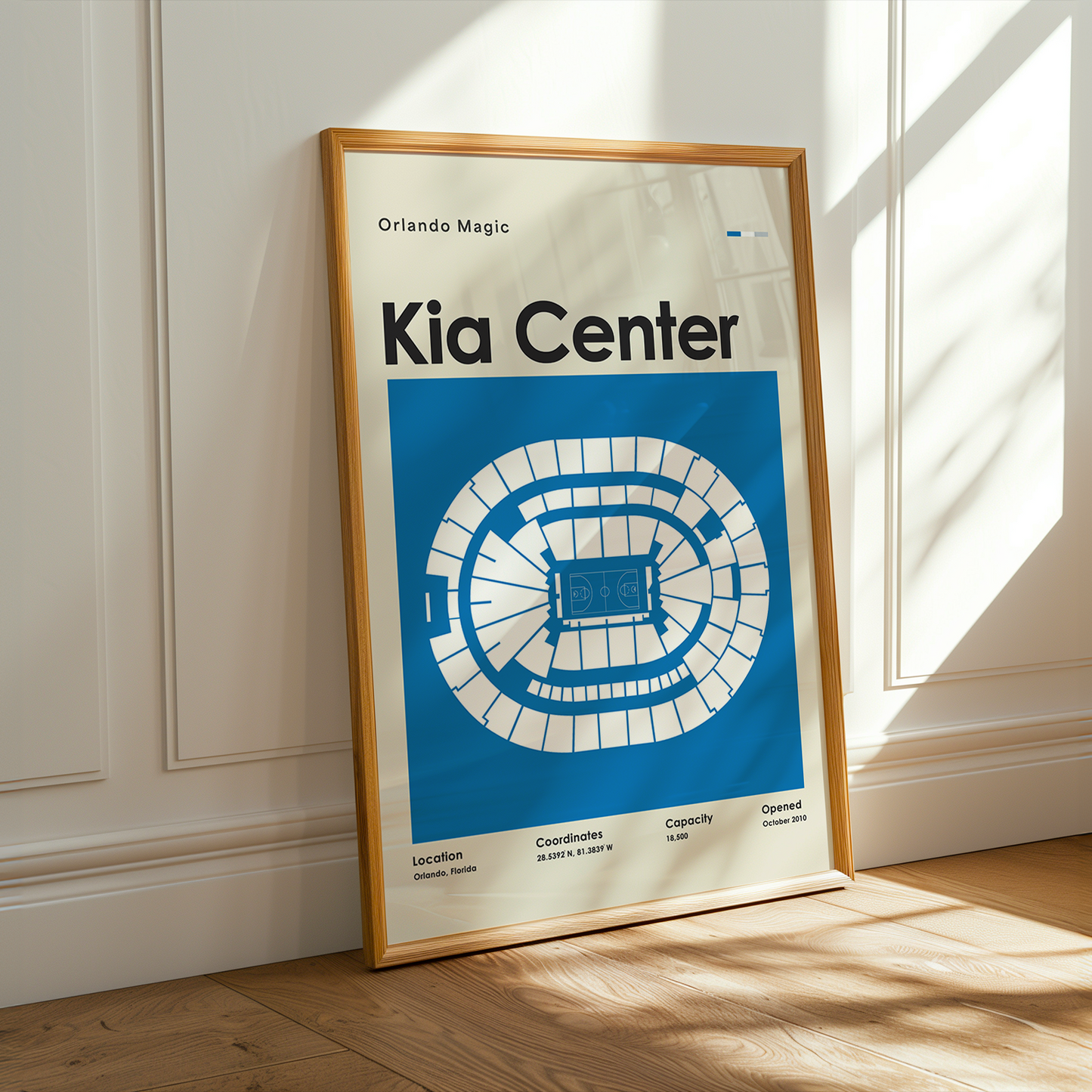 Framed poster of the Kia Center layout on a wooden floor with sunlight streaming through a window.