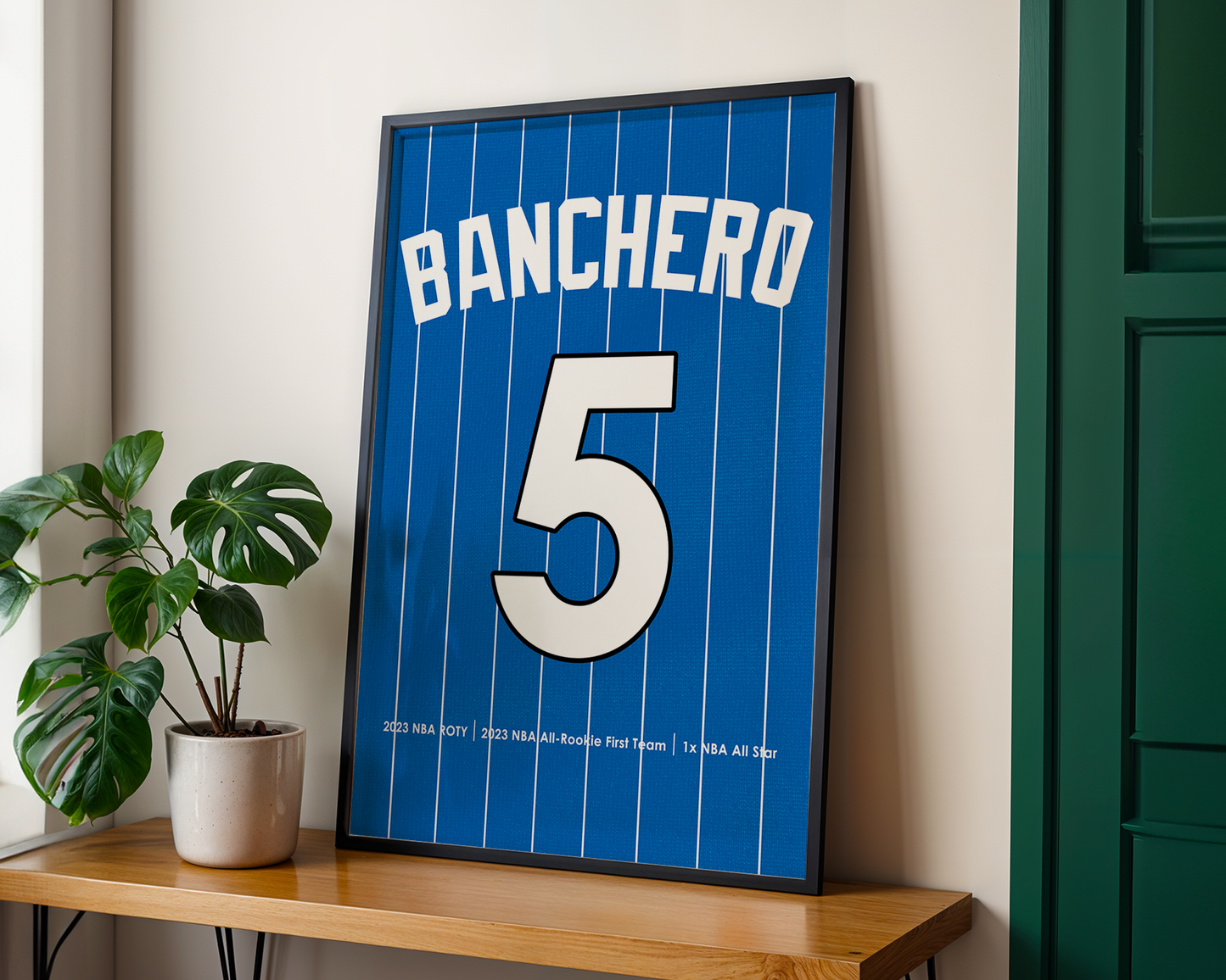 Framed sports jersey with 'Banchero' and number '5' on a wooden shelf.