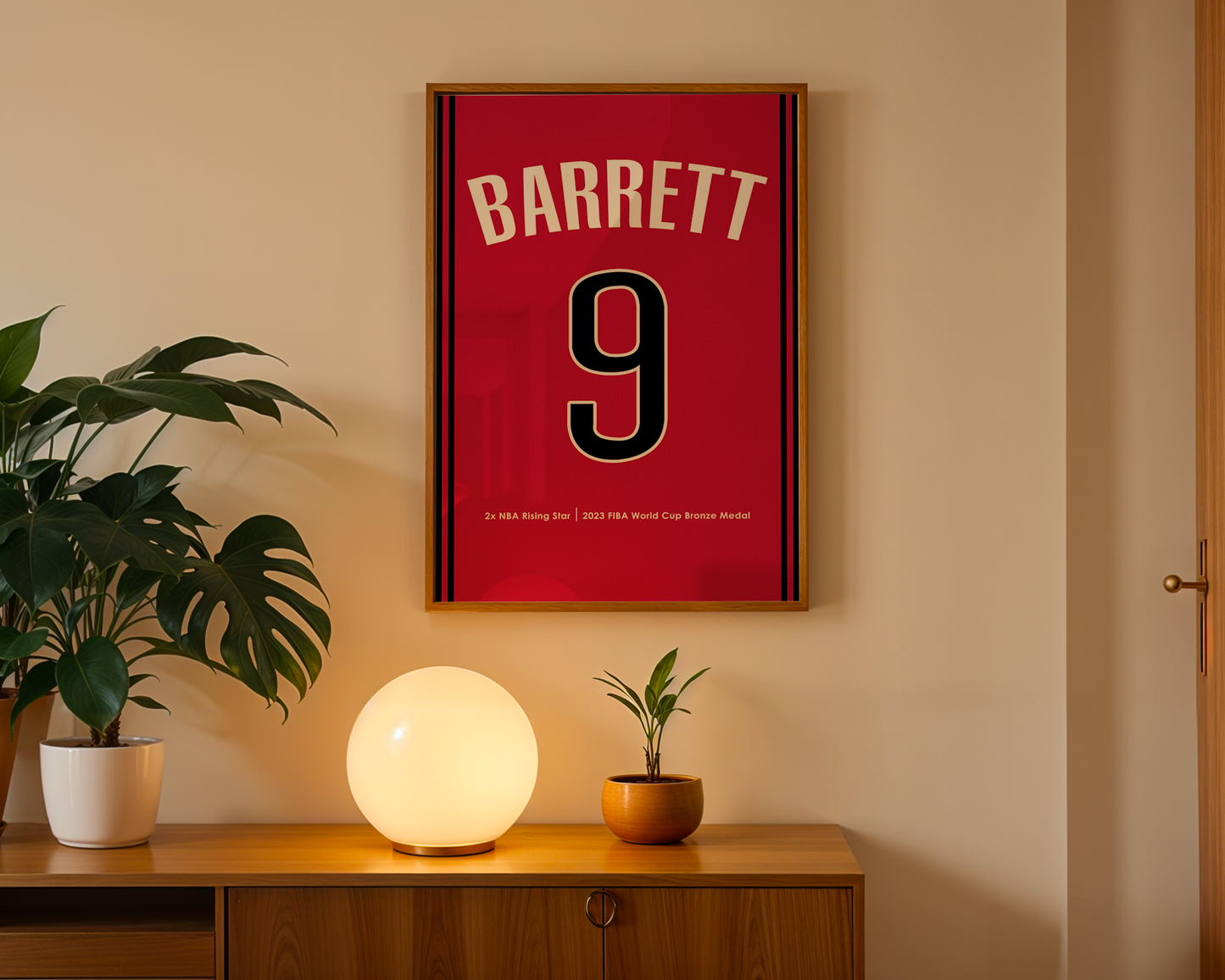 Framed red sports jersey with 'BARRETT 9' on a wall above a wooden cabinet with decorative items.