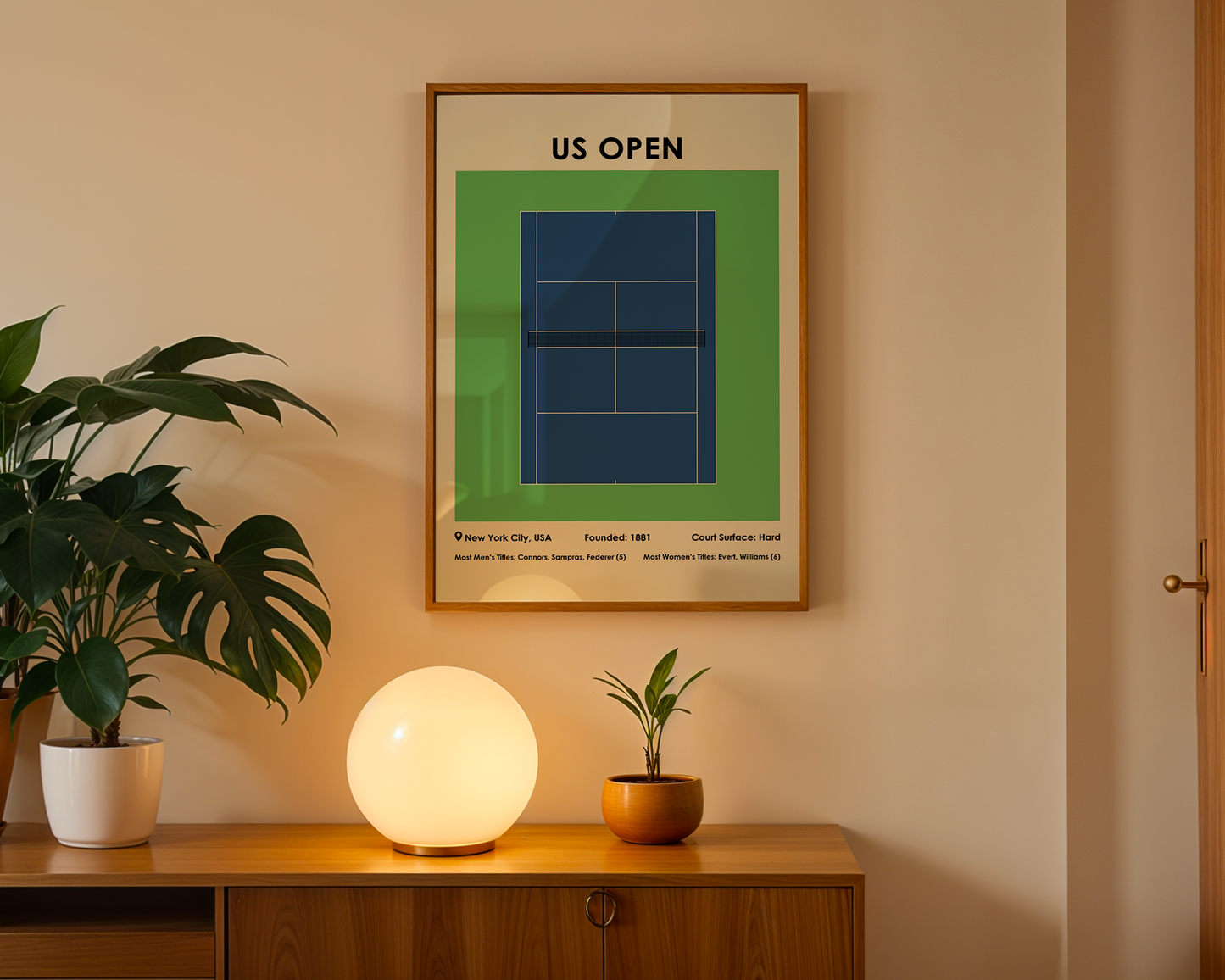 Framed US Open tennis court poster on a wall above a wooden cabinet with decorative items.