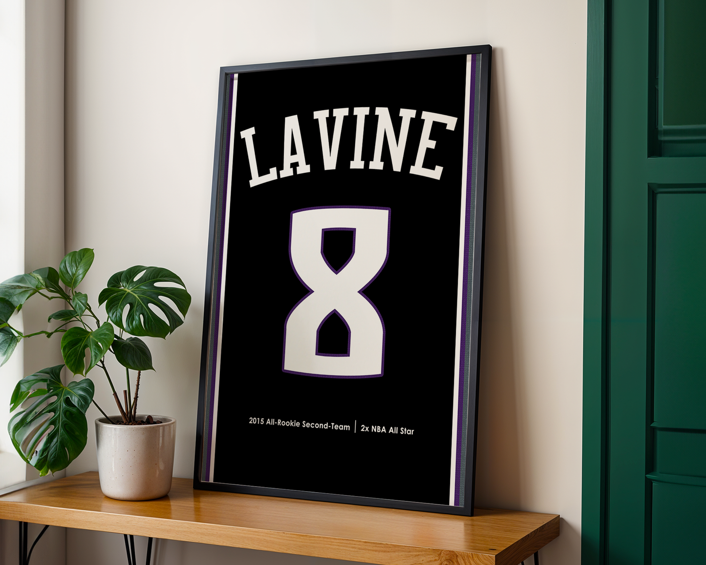 Framed poster with 'LAVINE' and hourglass design on a wall next to a plant and wooden shelf.