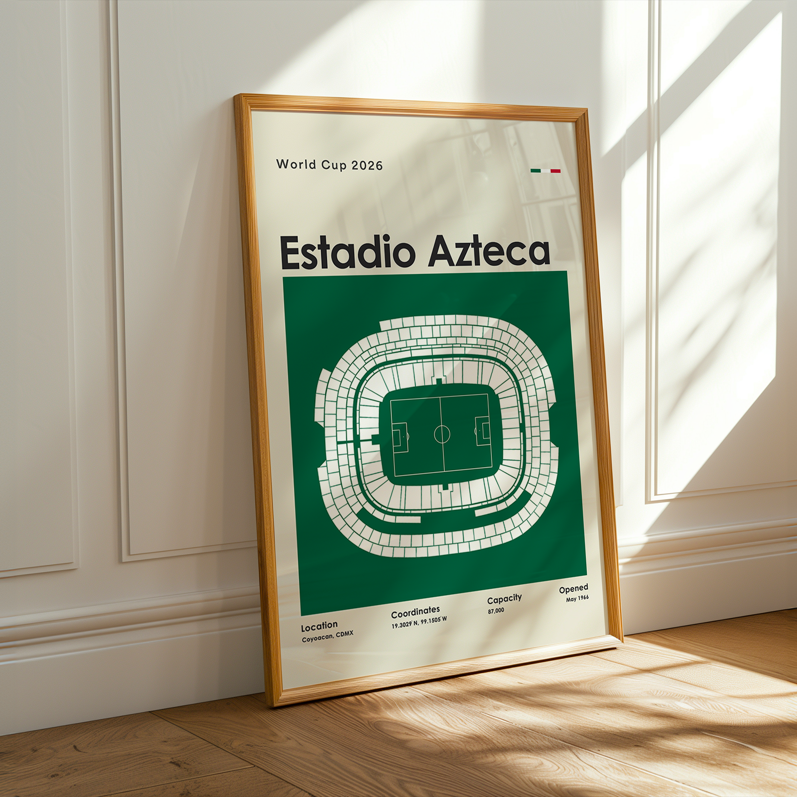 Framed poster of Estadio Azteca on a wooden floor with sunlight streaming through a window.