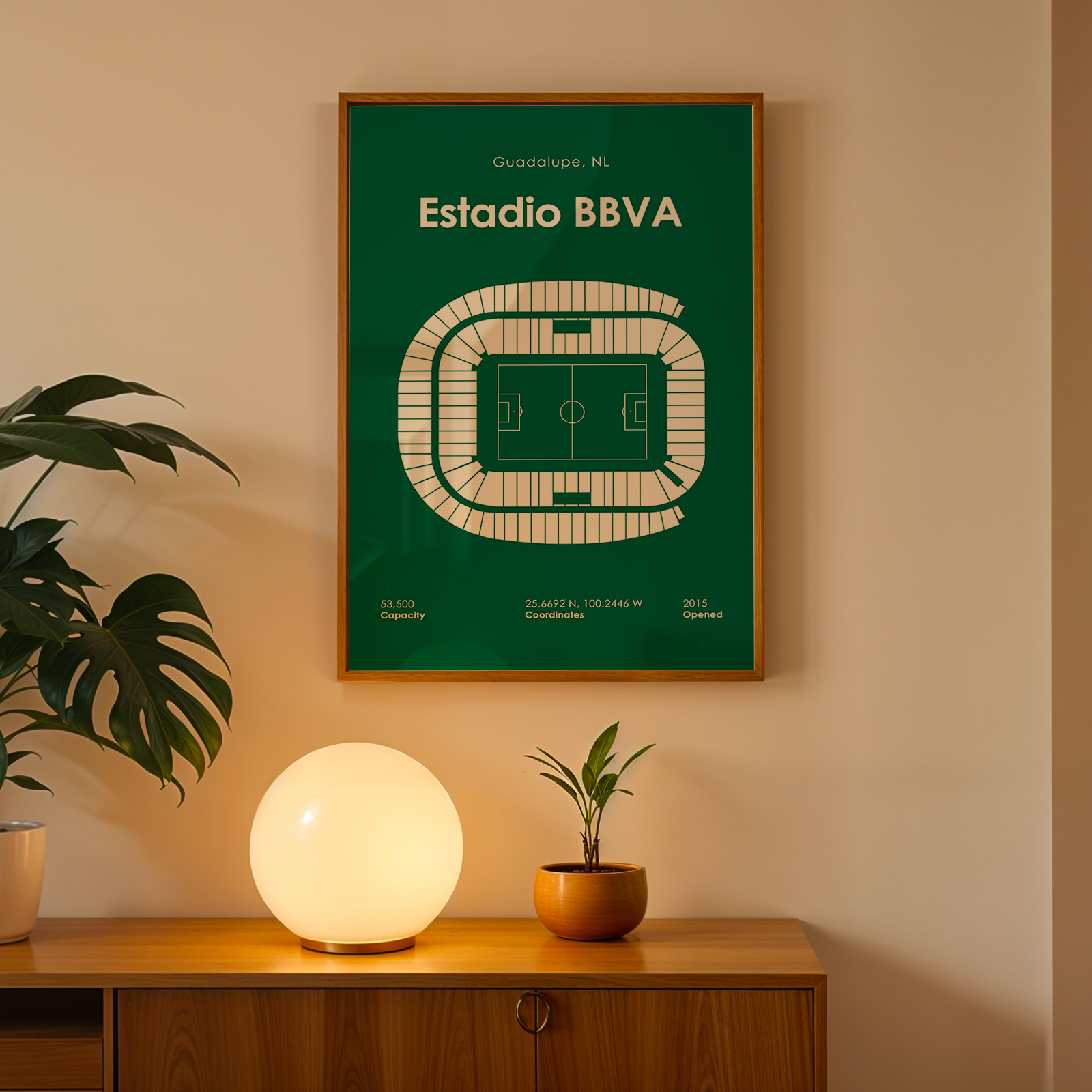 Framed poster of Estadio BBVA on a wall above a wooden cabinet with decorative items.