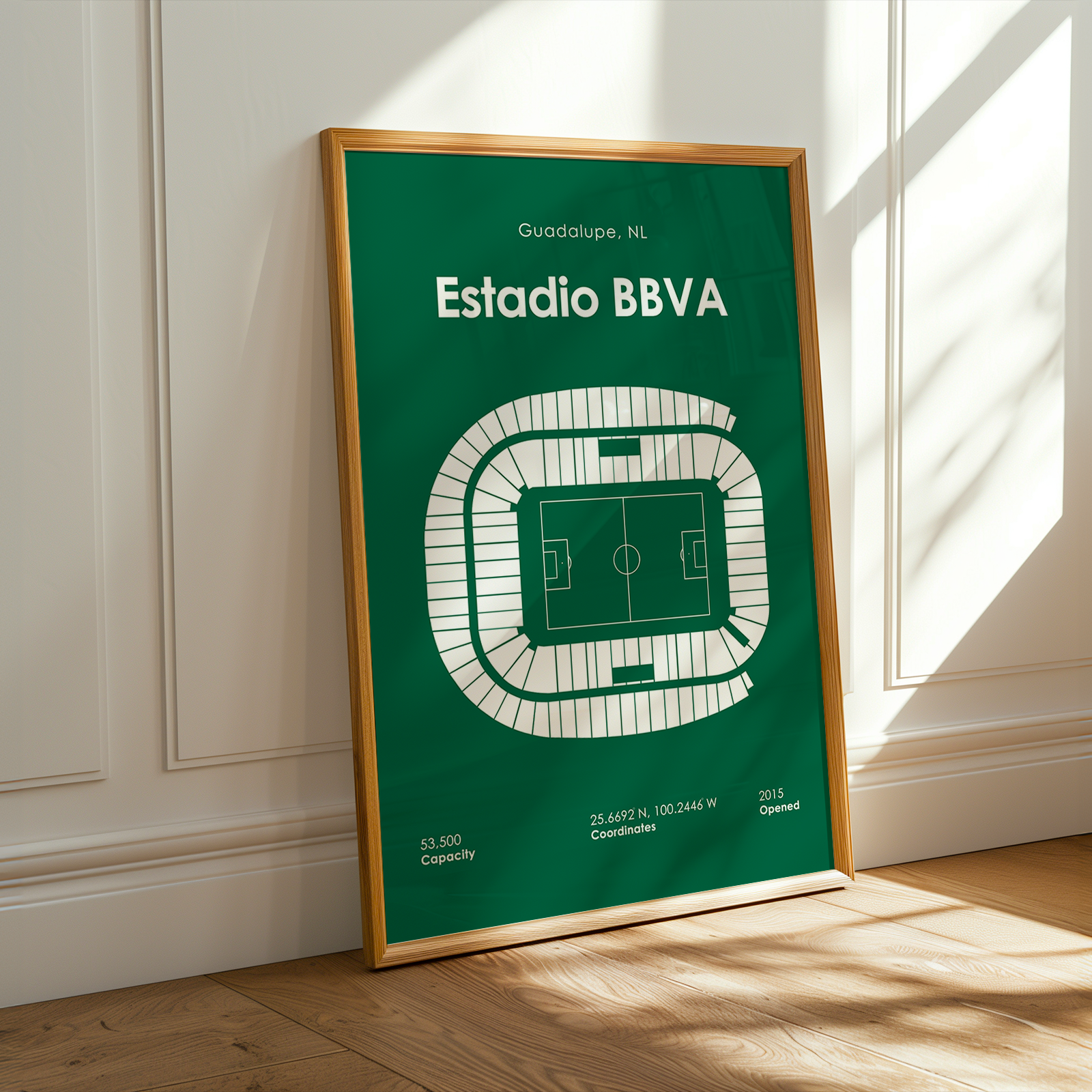 Framed poster of Estadio BBVA on a wooden floor with sunlight casting shadows.