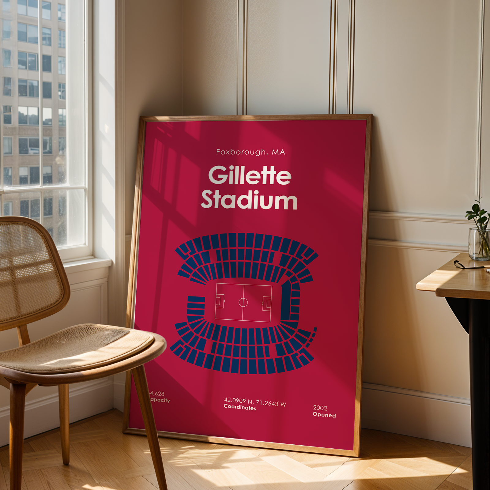 Poster of Gillette Stadium in a room with a chair and table.