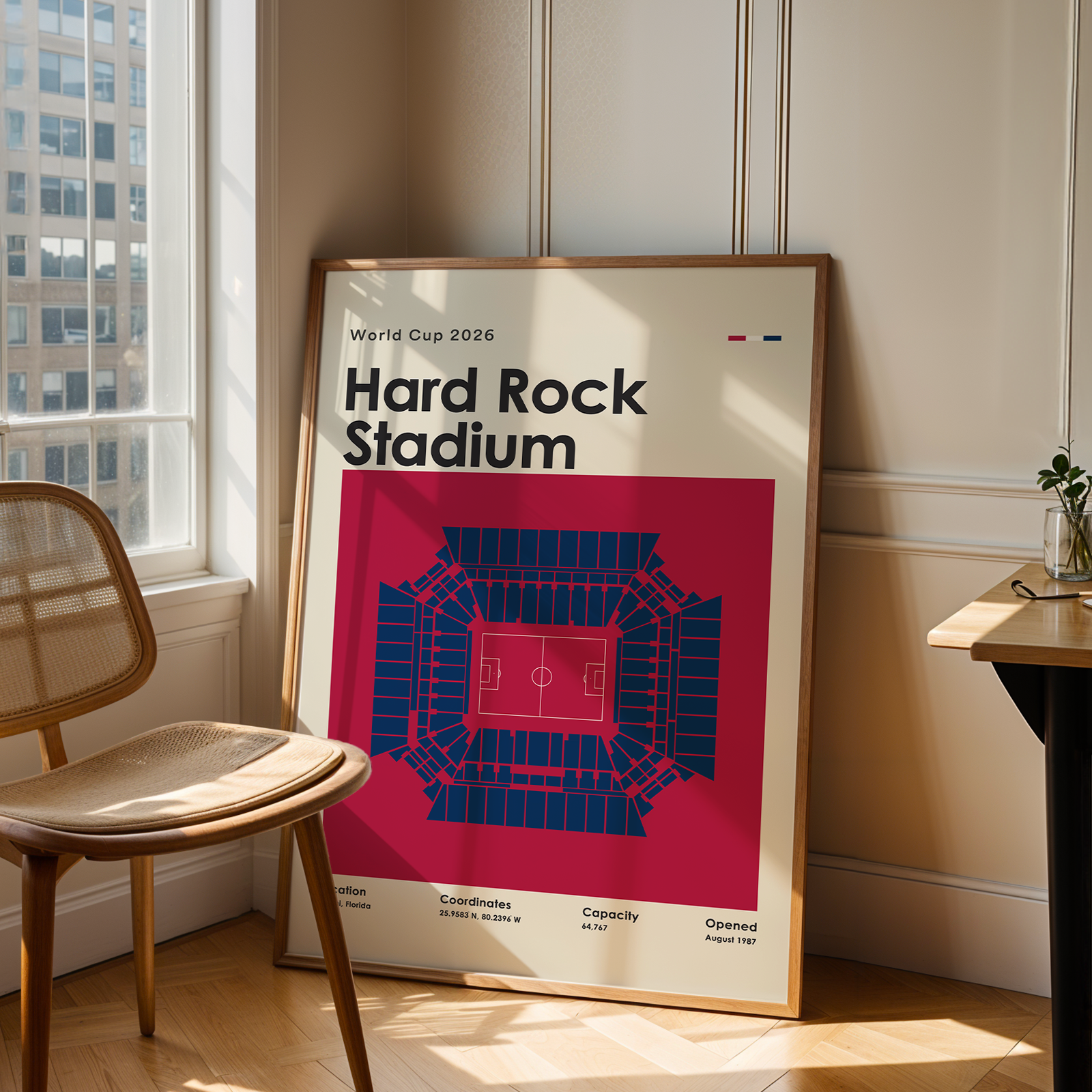 Framed poster of Hard Rock Stadium in a room with a chair and table.