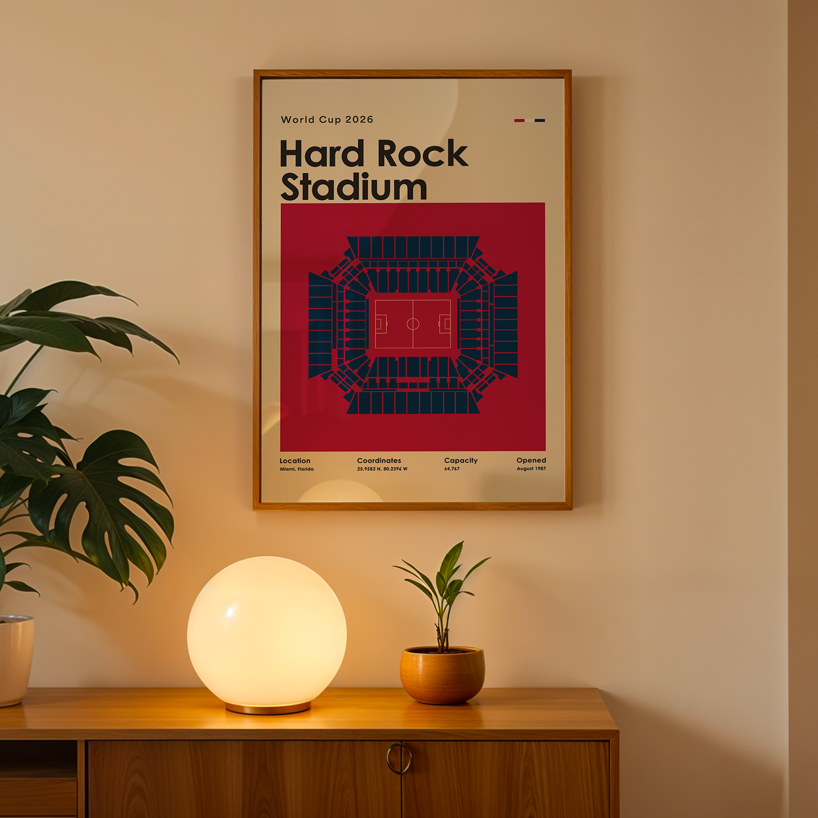 Framed poster of Hard Rock Stadium on a wall above a wooden cabinet with decorative items.