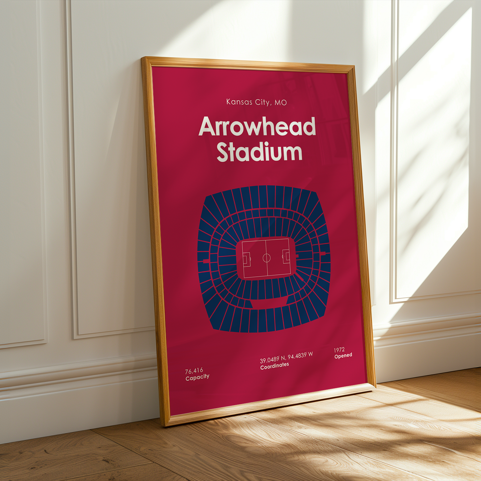Framed poster of Arrowhead Stadium on a wooden floor with sunlight casting shadows.