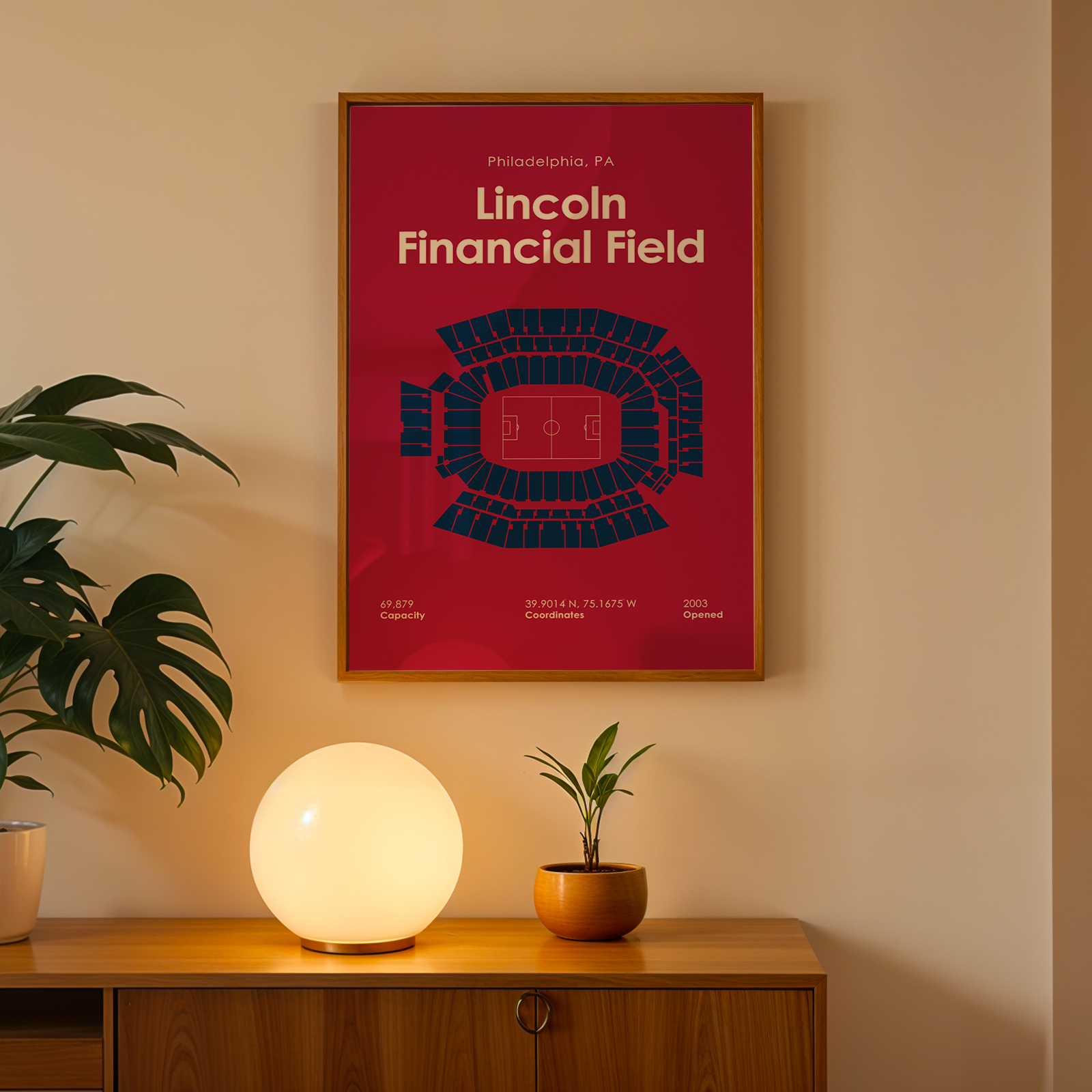 Framed poster of Lincoln Financial Field on a wall above a wooden cabinet with decorative items.