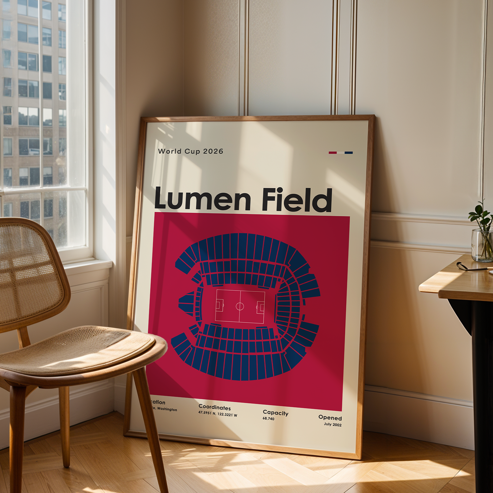 Framed poster of Lumen Field in a room with a chair and table.