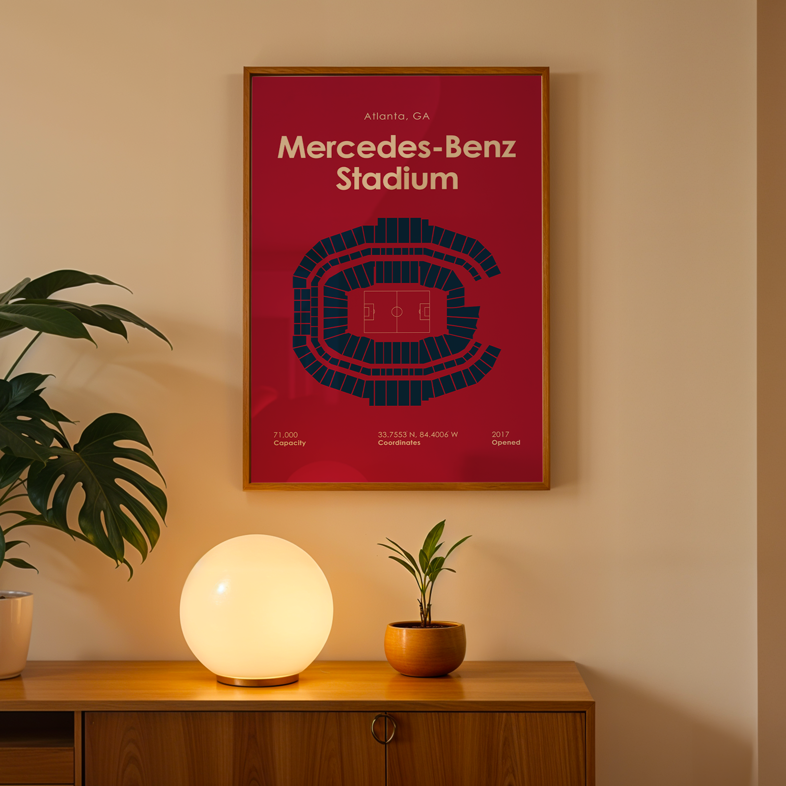 Framed poster of Mercedes-Benz Stadium on a wall above a wooden cabinet with decorative items.