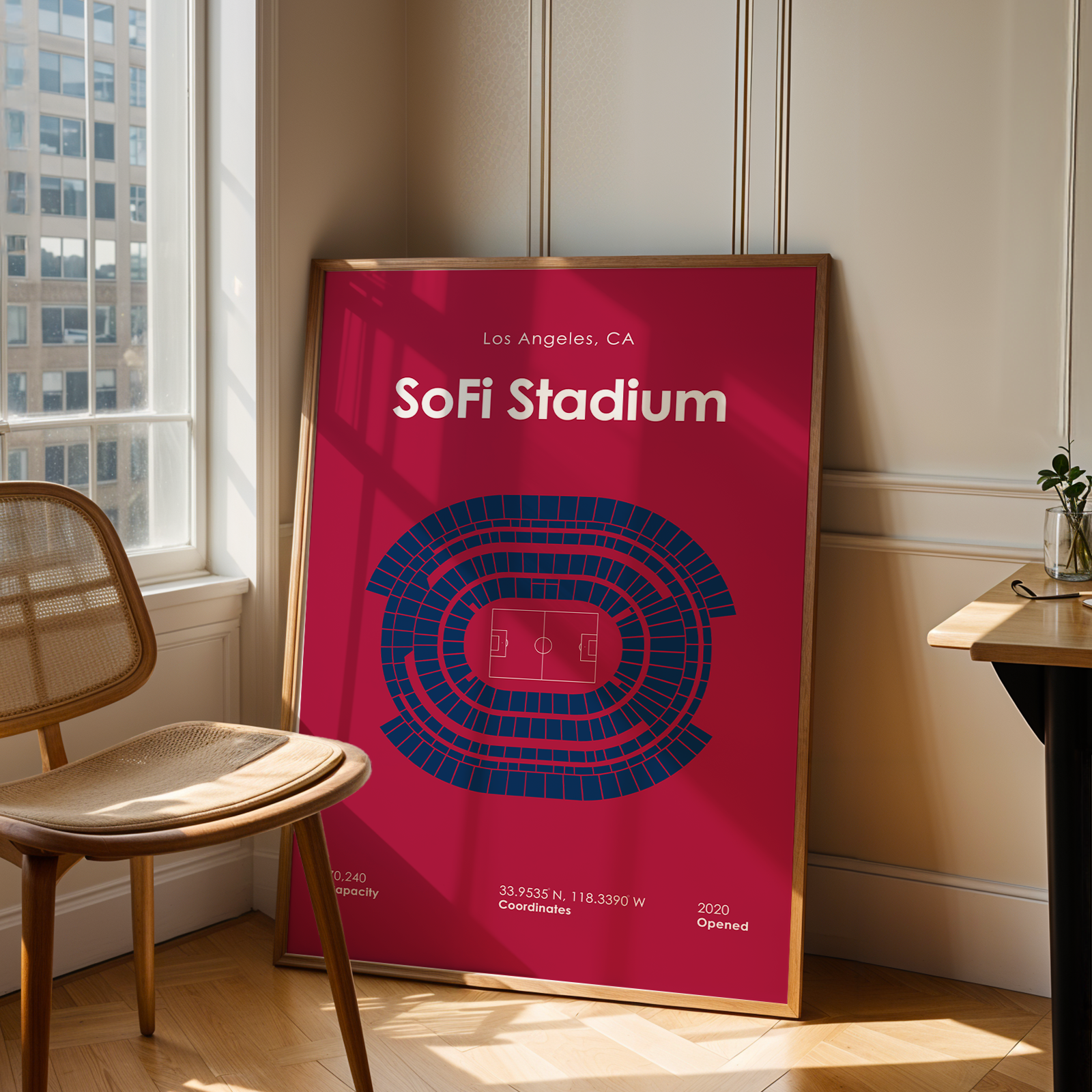 Poster of Sofi Stadium in Los Angeles, CA, leaning against a wall in a room with a chair and table.