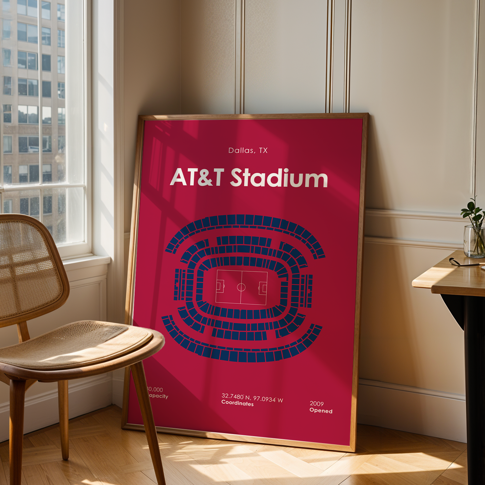Framed poster of AT&T Stadium in a room with a chair and table.
