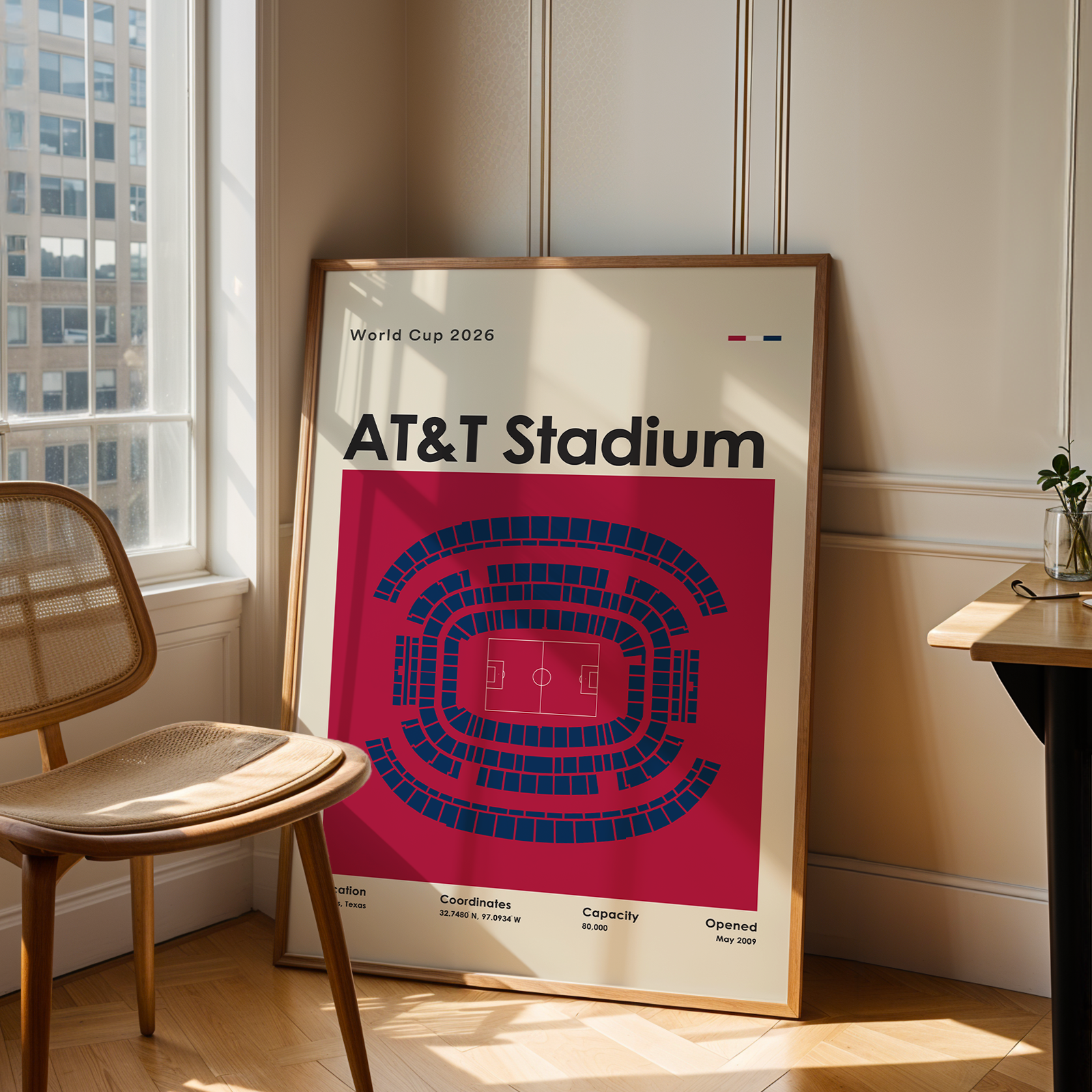 Framed poster of AT&T Stadium in a room with a chair and table.