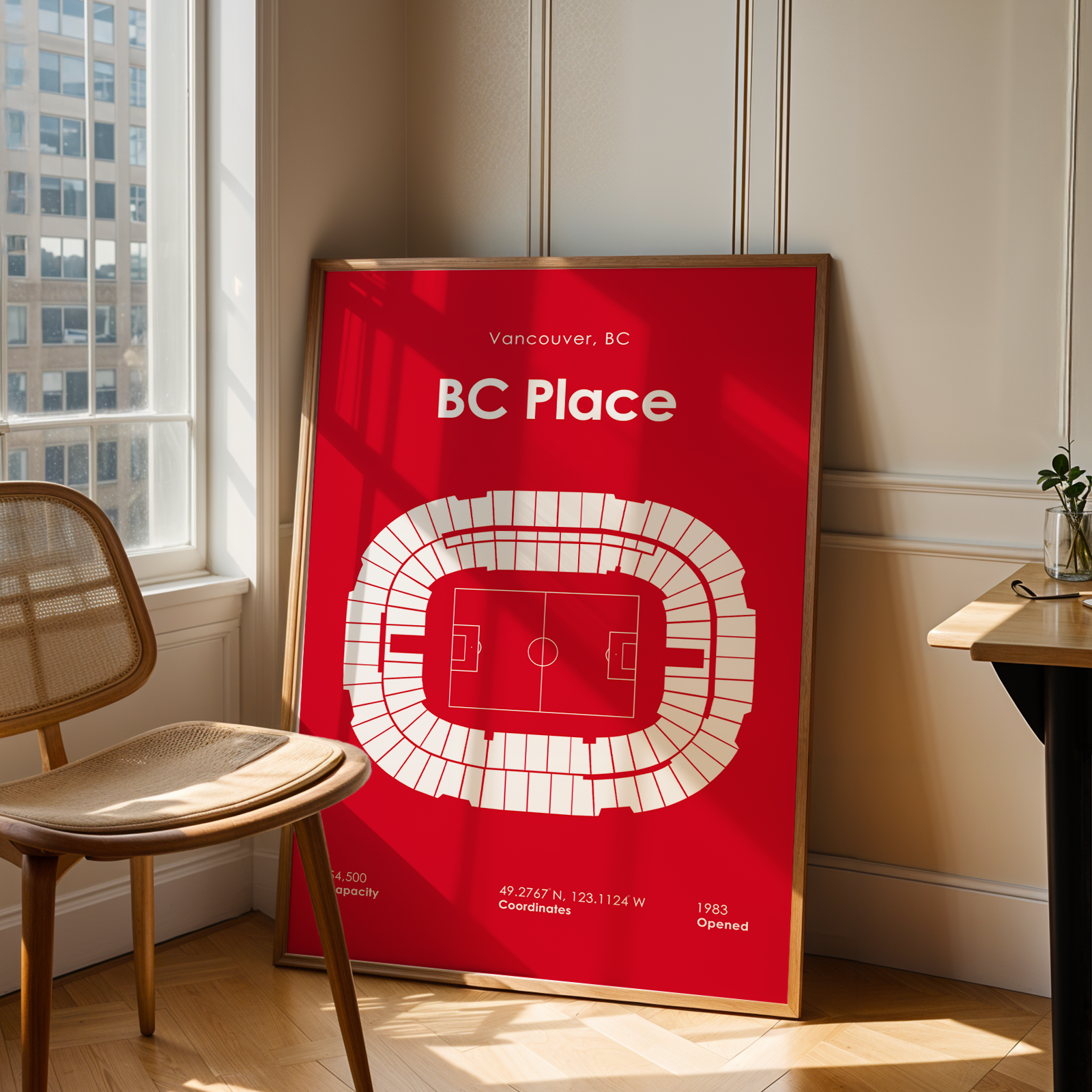 Red poster of BC Place stadium in a room with a chair and table.