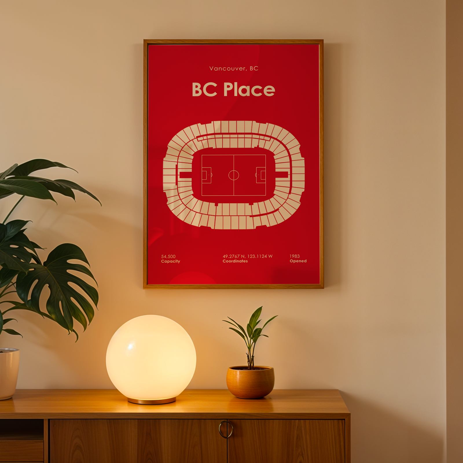 Framed poster of BC Place on a wall above a wooden cabinet with decorative items.
