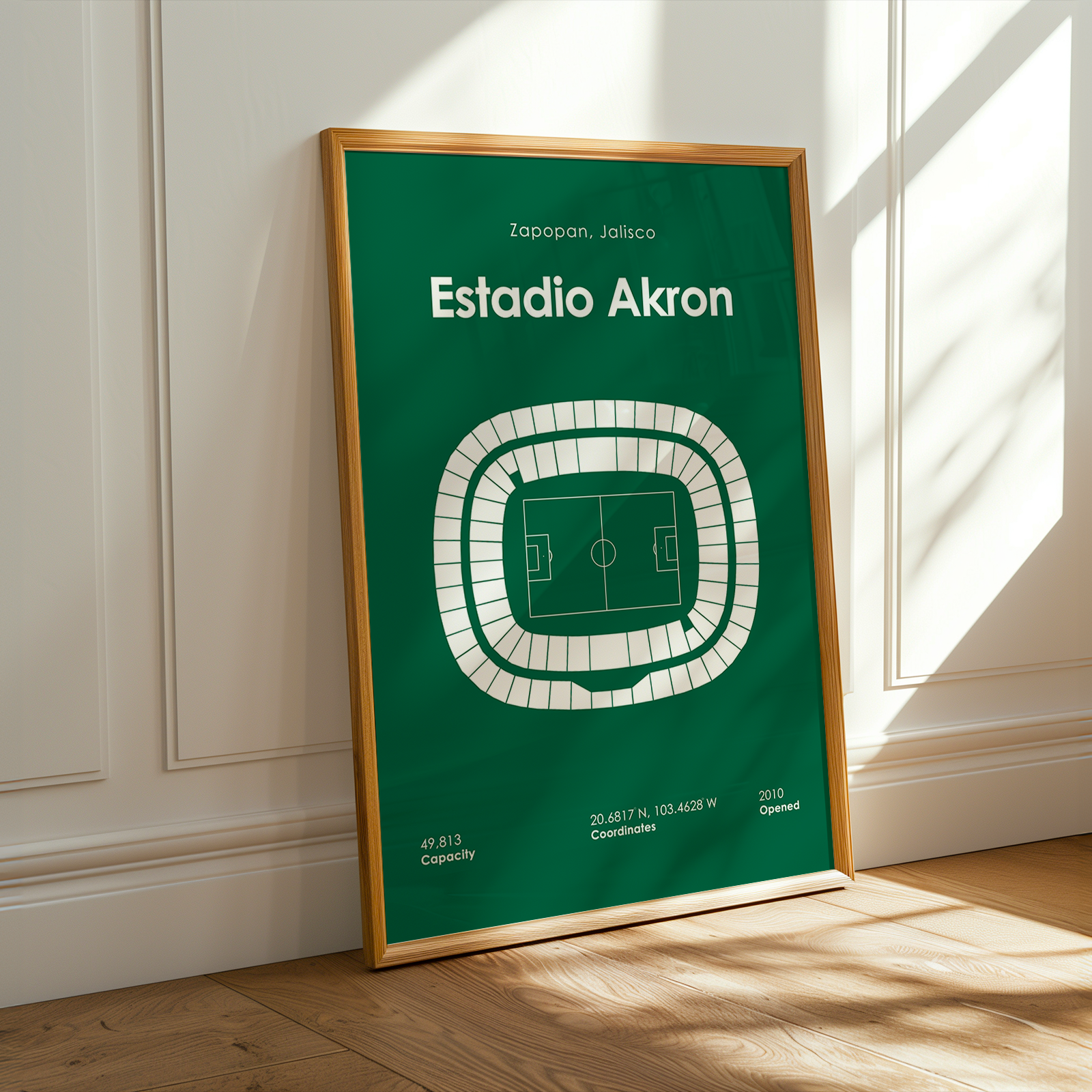 Framed poster of Estadio Akron on a wall with sunlight casting shadows.