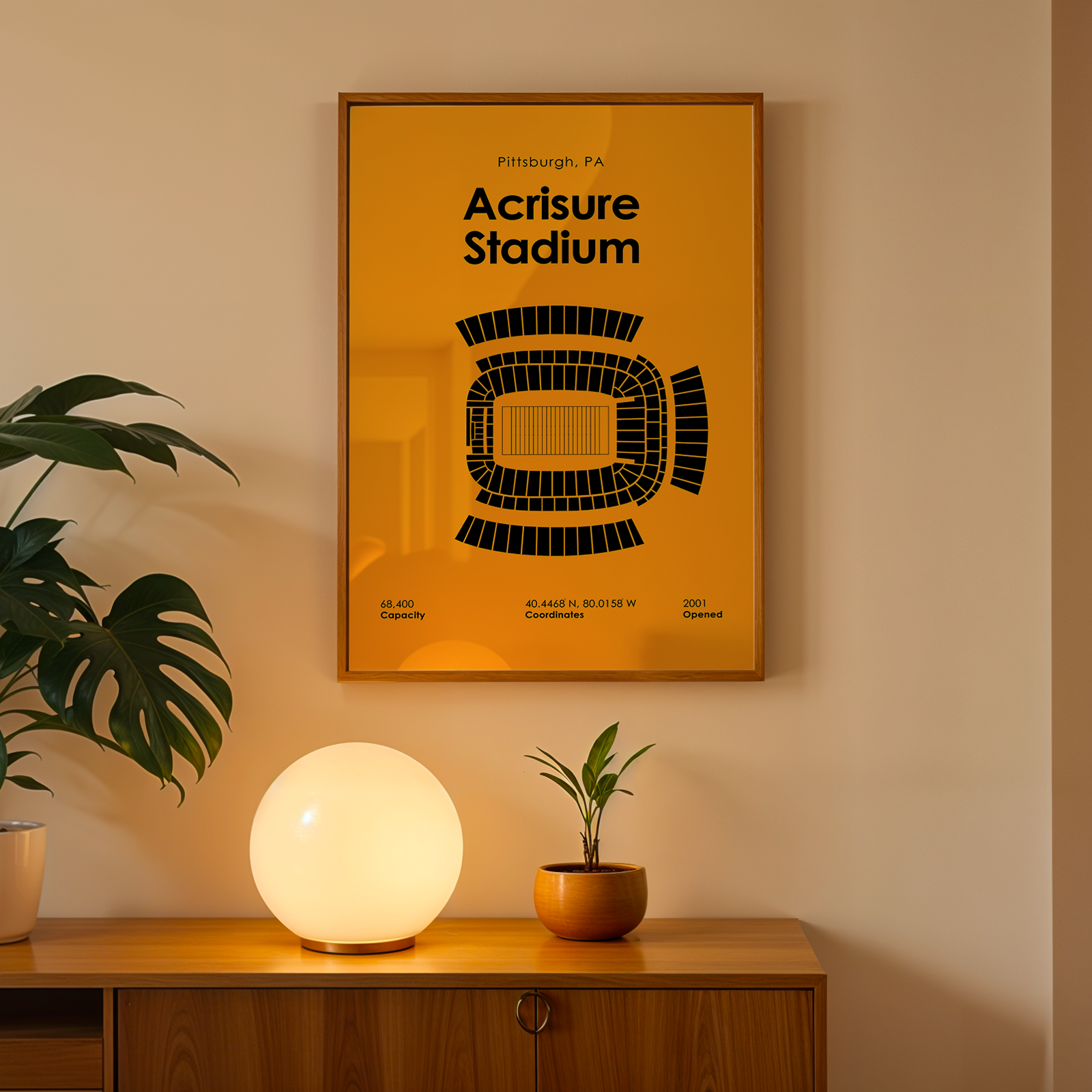 Framed poster of Acquisure Stadium on a wall above a wooden cabinet with decorative items.