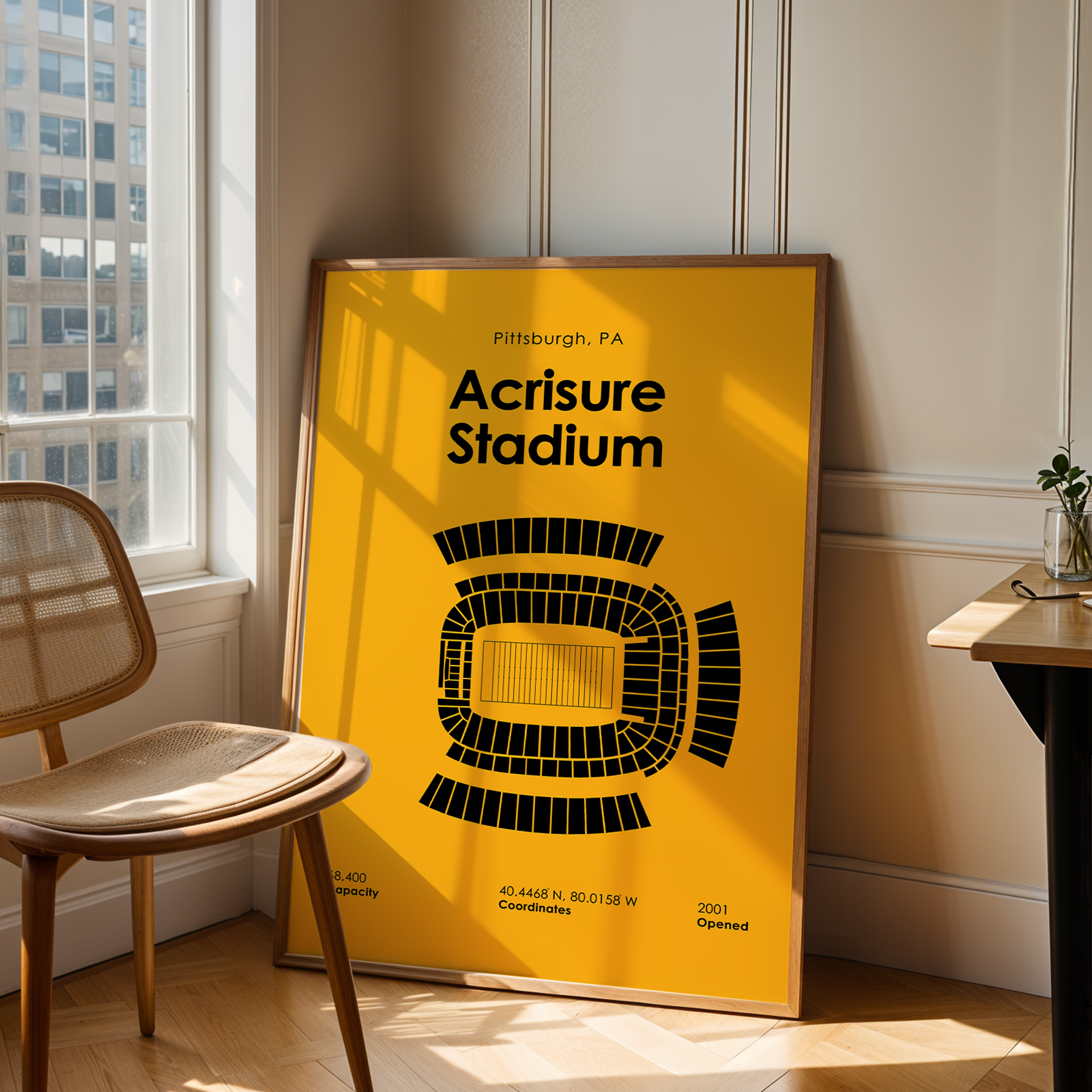 Poster of Acquisure Stadium in Pittsburgh, PA, leaning against a wall in a room with a chair and table.