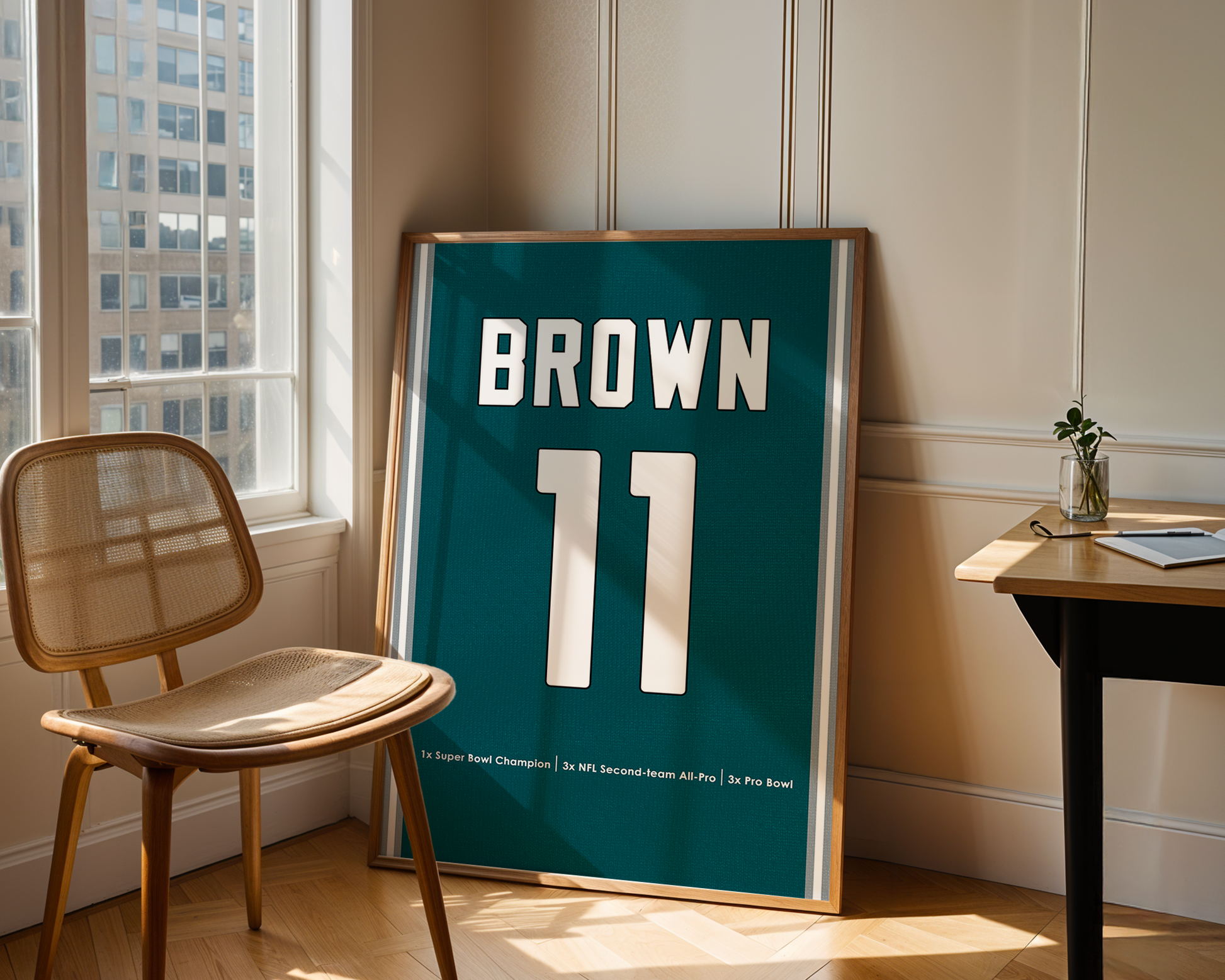 Framed sports jersey with 'Brown 11' in a room with a window and chair.