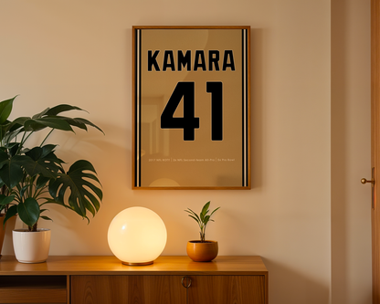 Framed artwork with 'KAMARA 41' on a wall above a wooden cabinet with decorative items.