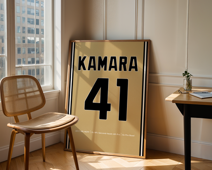 Framed sports jersey with 'KAMARA 41' in a room with a window and chair.