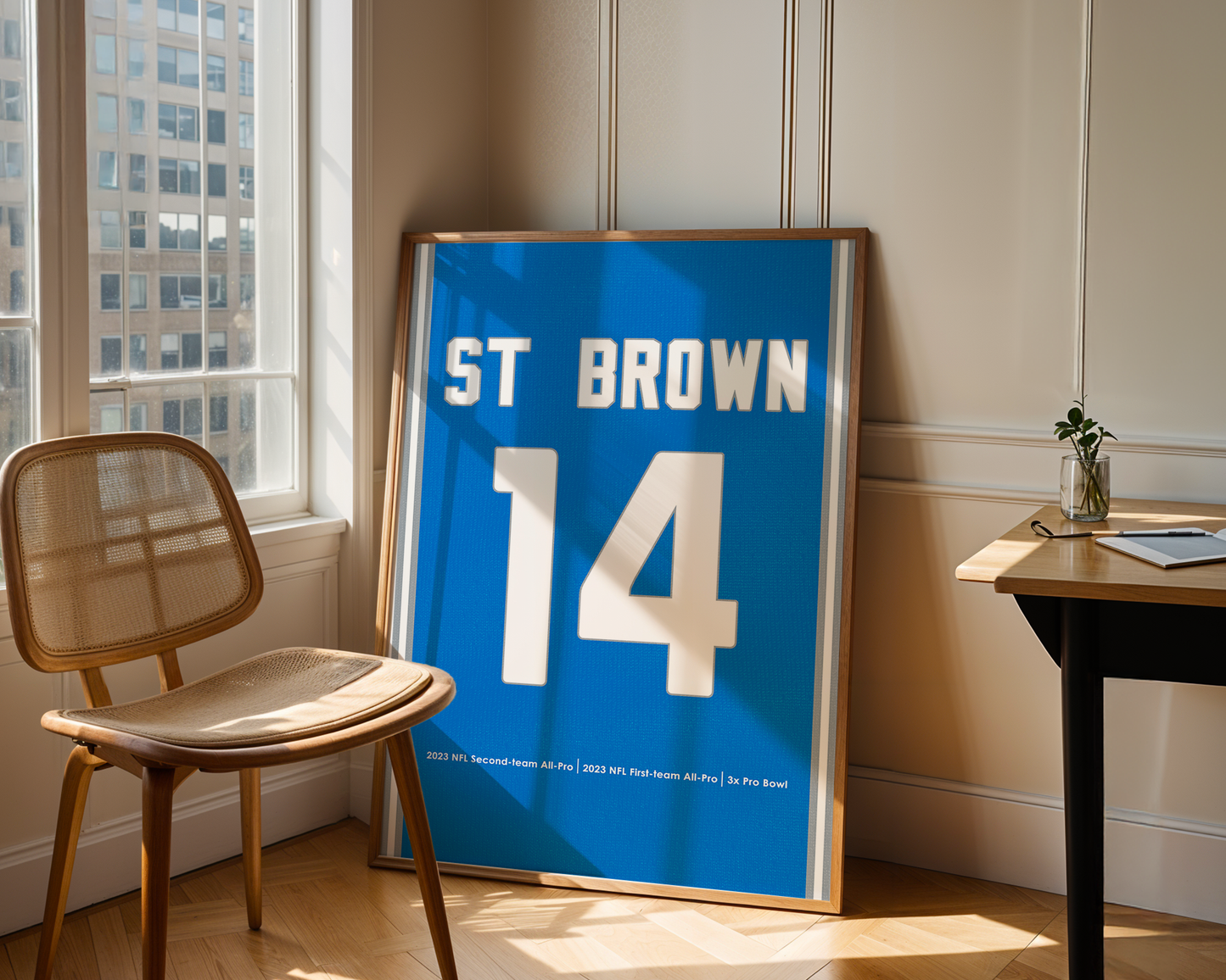 Framed sports jersey with 'ST BROWN 14' on a wall in a room with a chair and table.
