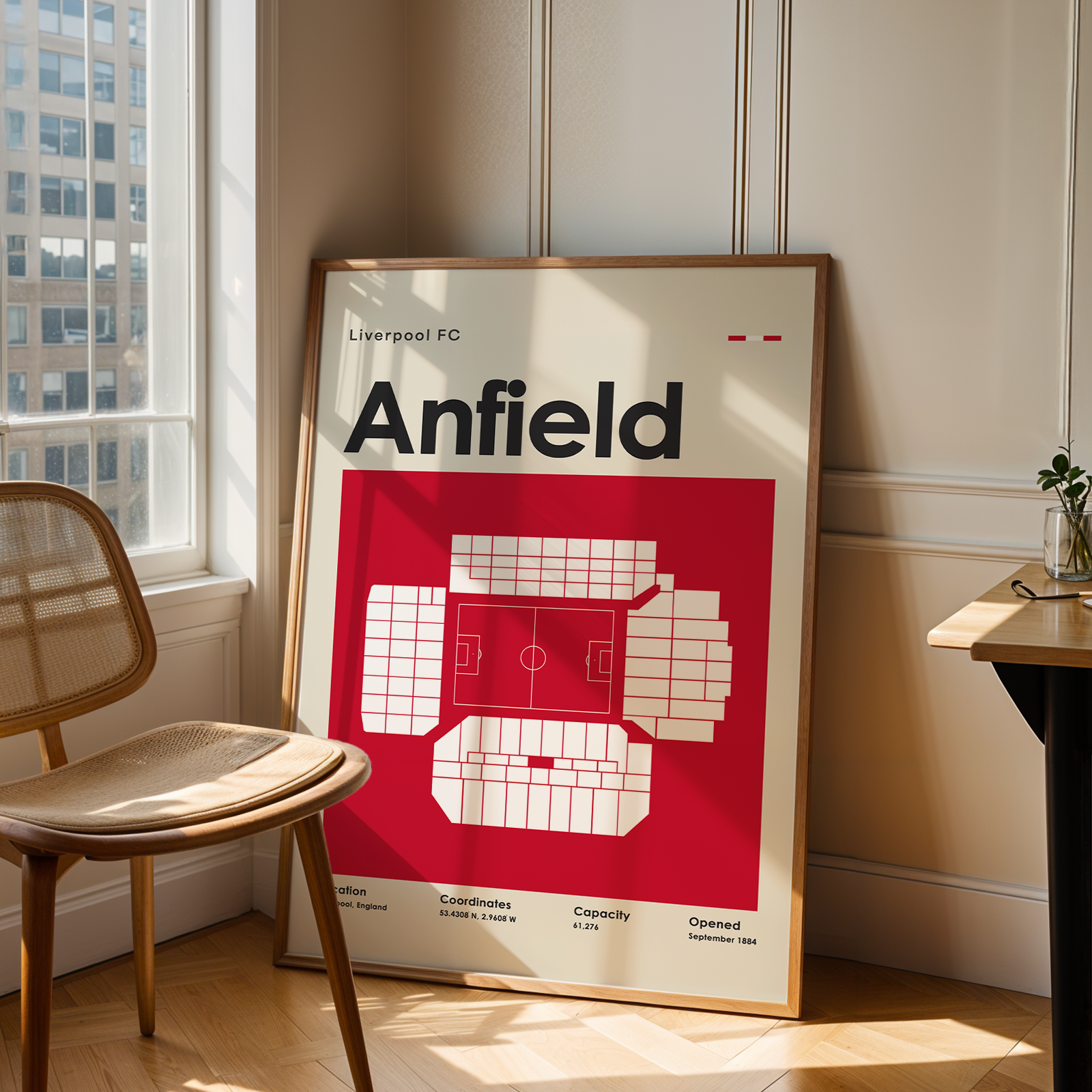Framed poster of Anfield stadium layout in a room with a chair and window.