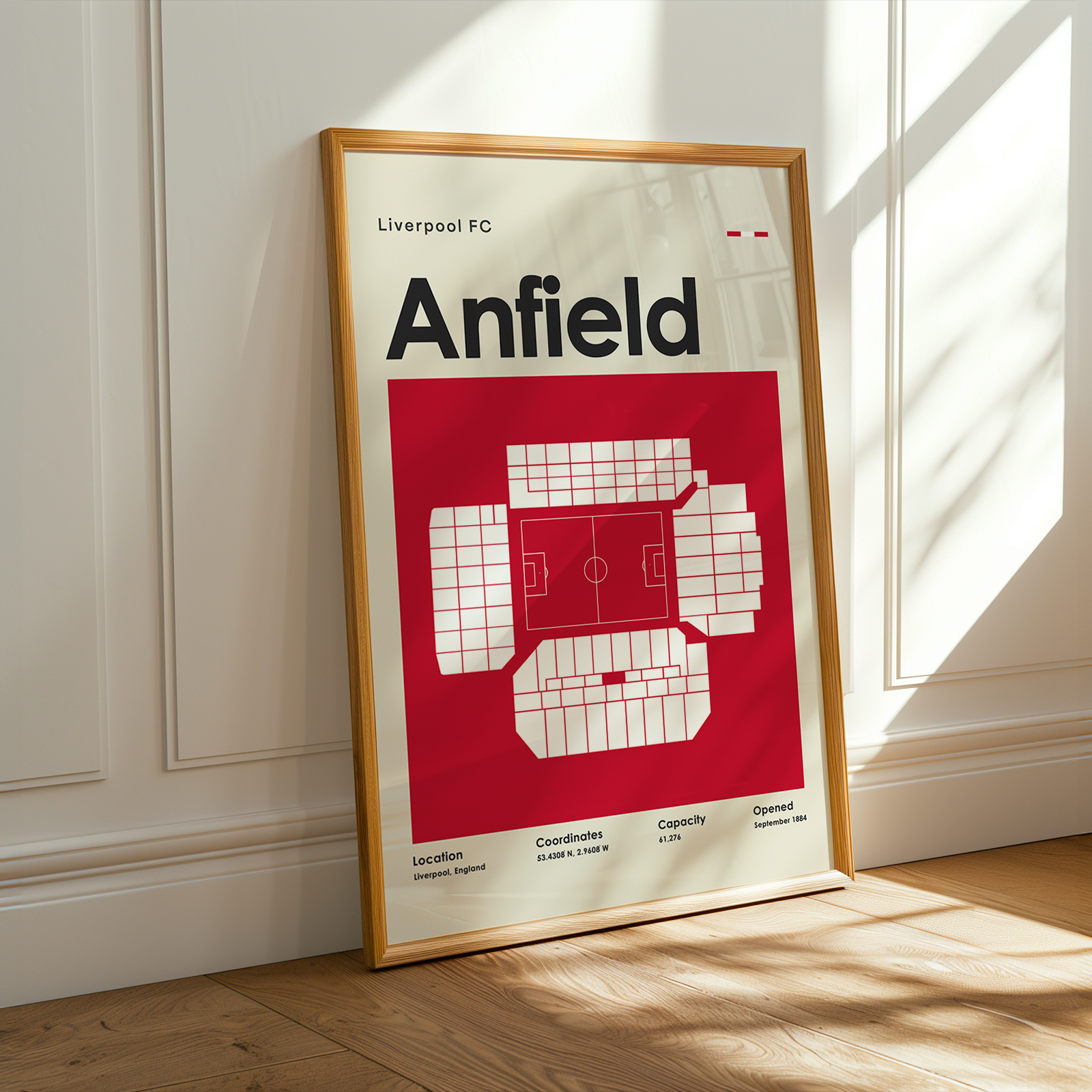 Framed poster of Anfield stadium layout with Liverpool FC branding on a wall.