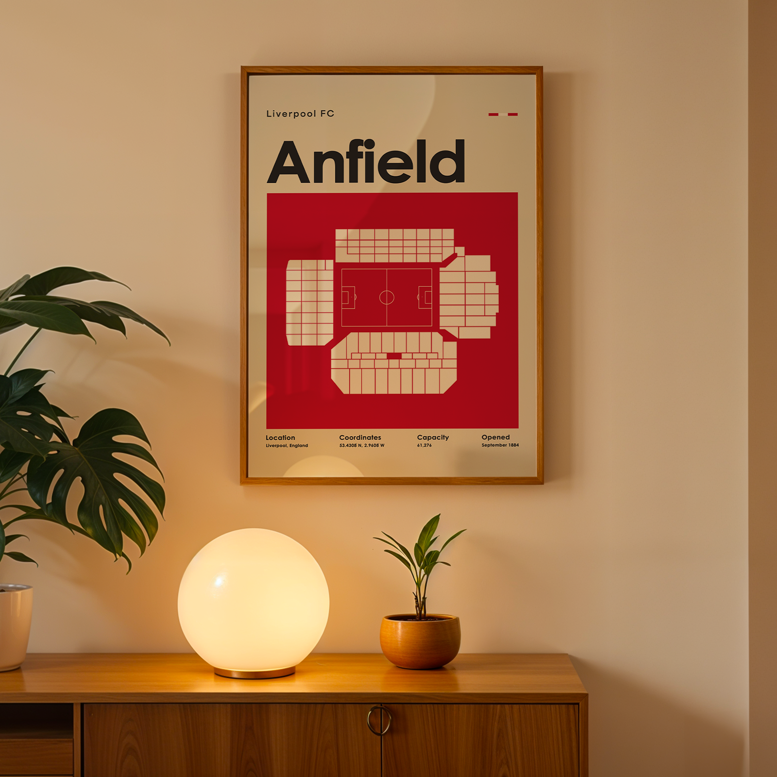 Framed poster of Anfield stadium on a wall above a wooden cabinet with decorative items.