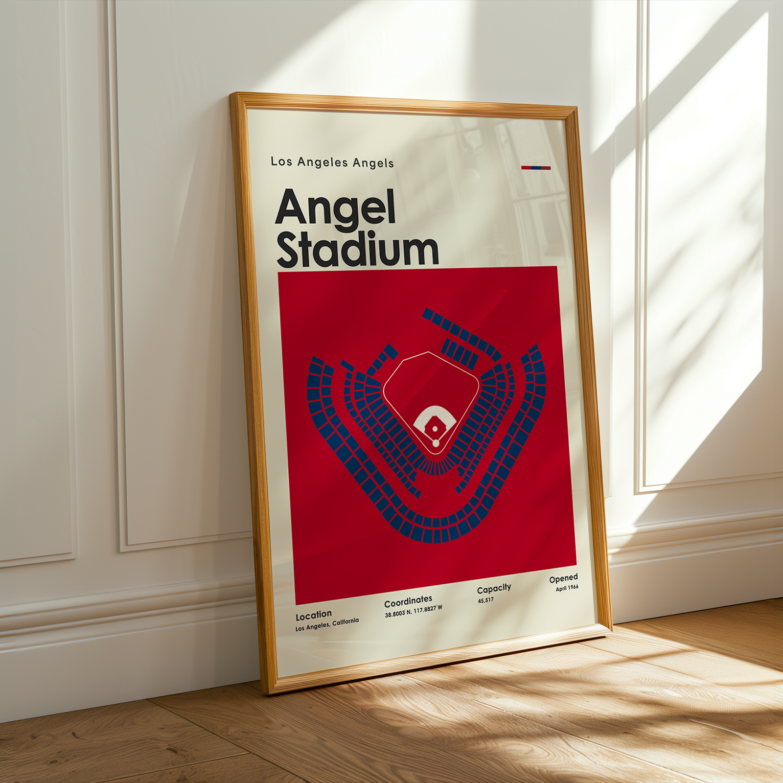 Framed poster of Los Angeles Angels Angel Stadium on a wooden floor with sunlight streaming through a window.