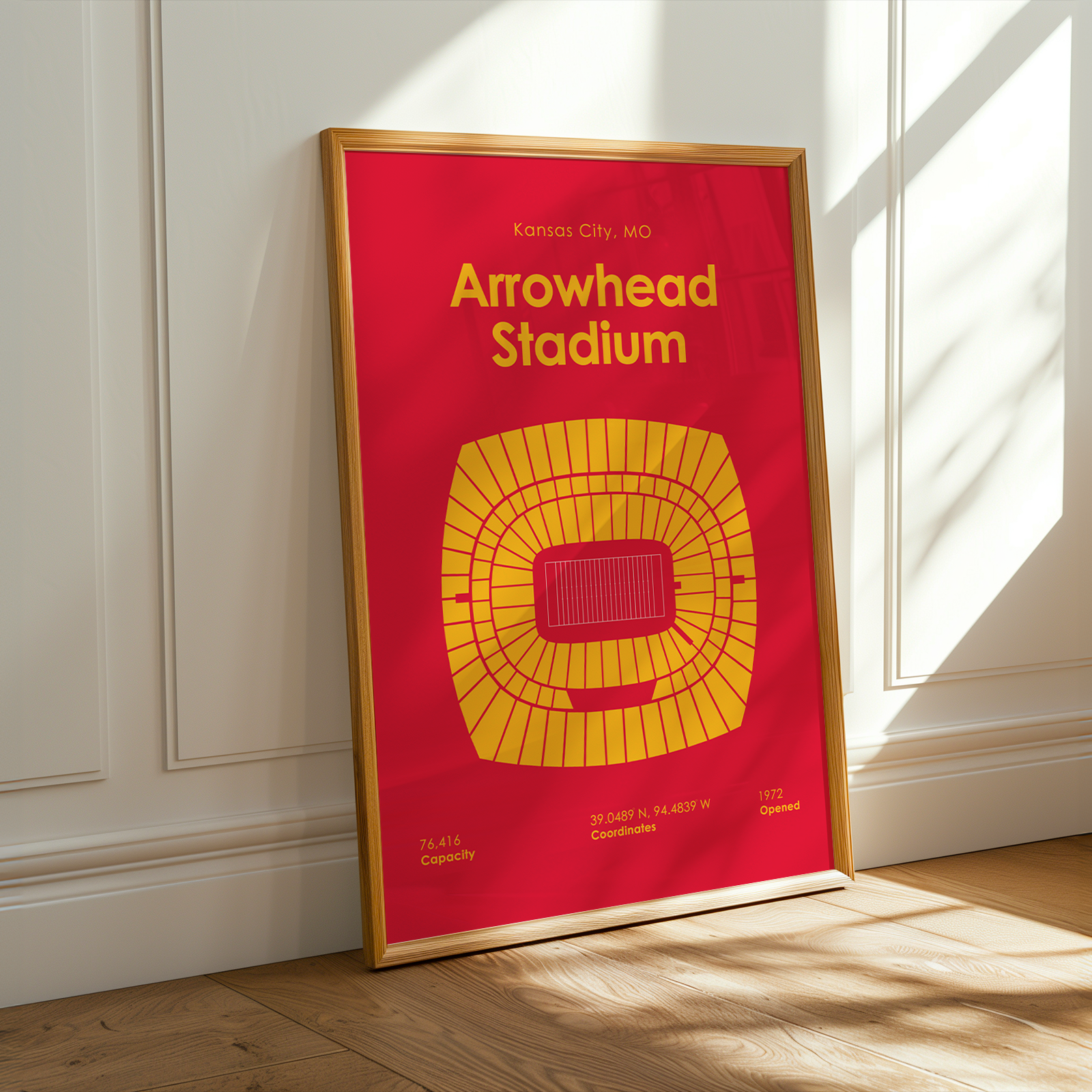 Framed poster of Arrowhead Stadium on a wooden floor with sunlight casting shadows.