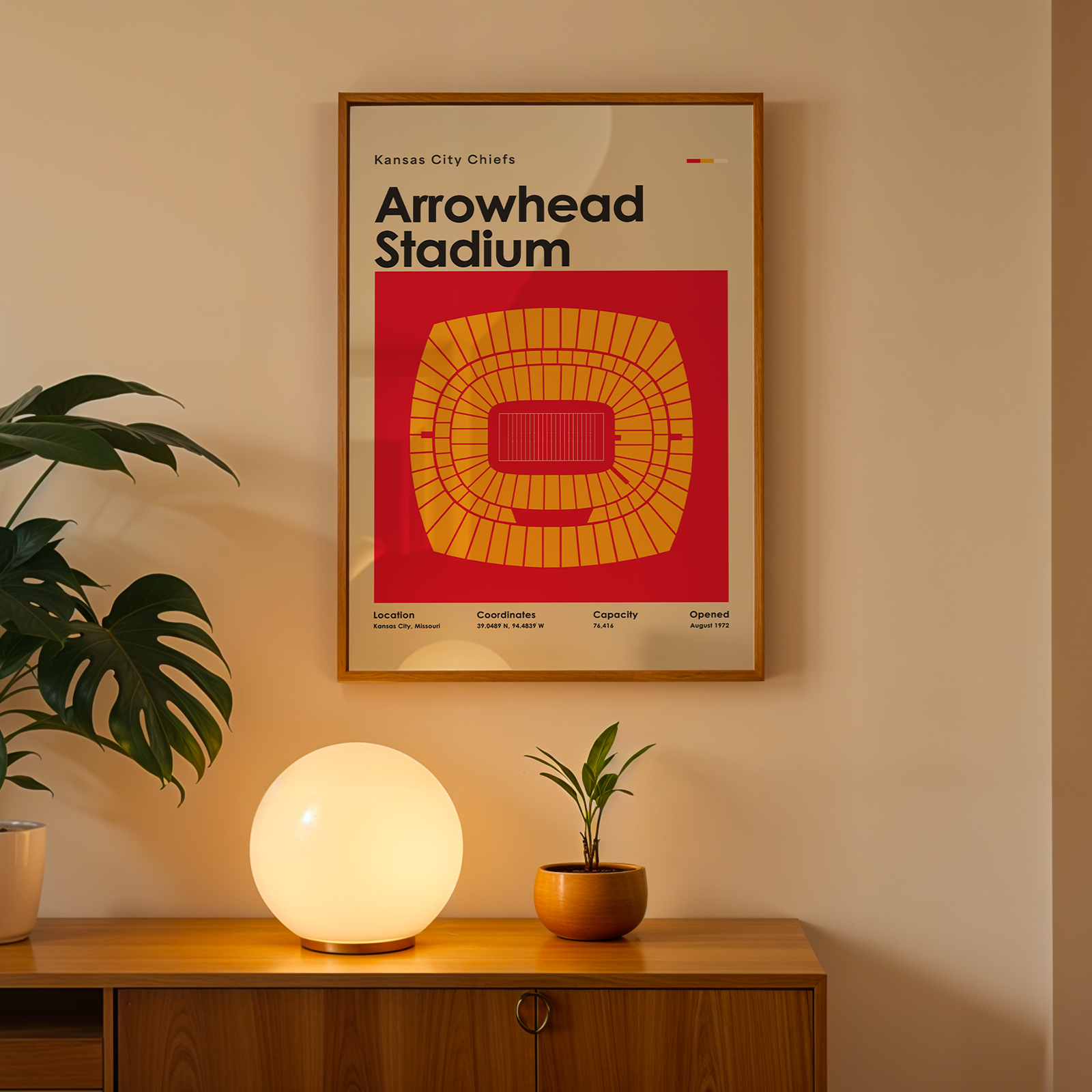 Framed poster of Arrowhead Stadium on a wall above a wooden cabinet with decorative items.