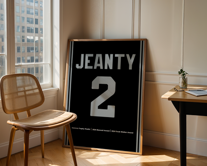 Framed poster with 'JEANTY 2' text in a room with a chair and table.