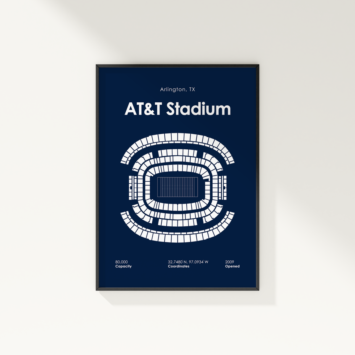 A framed minimalist poster of AT&T Stadium in Arlington, TX, featuring a white stadium seating diagram on a dark navy blue background, hanging on a light off-white wall.