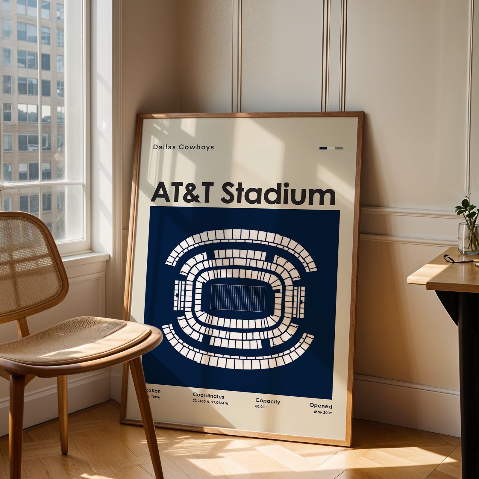 Framed poster of AT&T Stadium in a room with a chair and window.