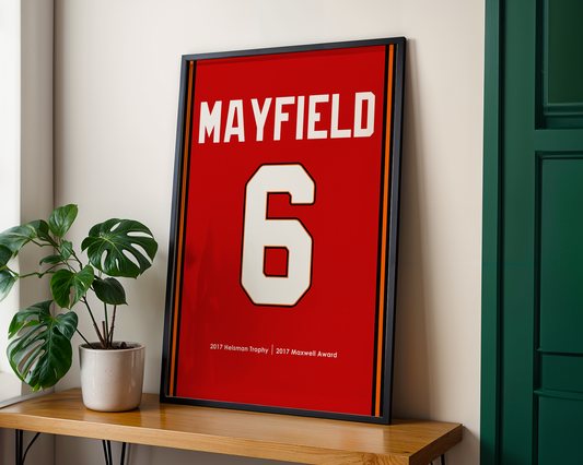 Framed sports jersey with 'MAYFIELD' and number '6' on a wooden shelf.