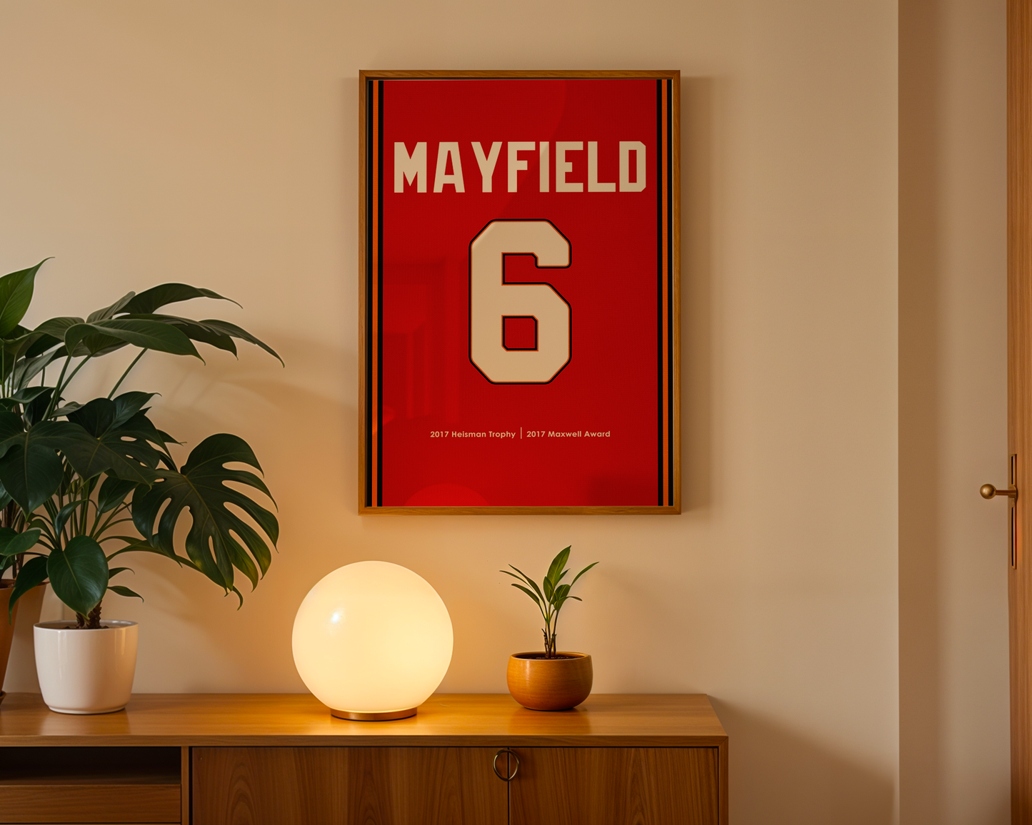 Framed sports jersey with 'Mayfield' and number '6' on a wall above a wooden cabinet with decorative items.