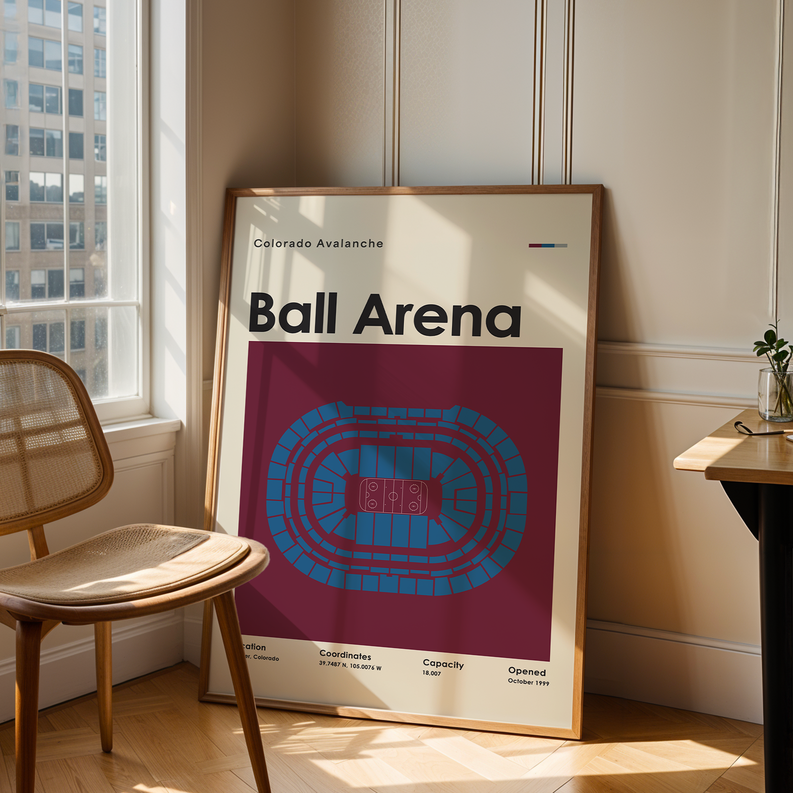 Framed poster of Ball Arena in a room with a chair and table.