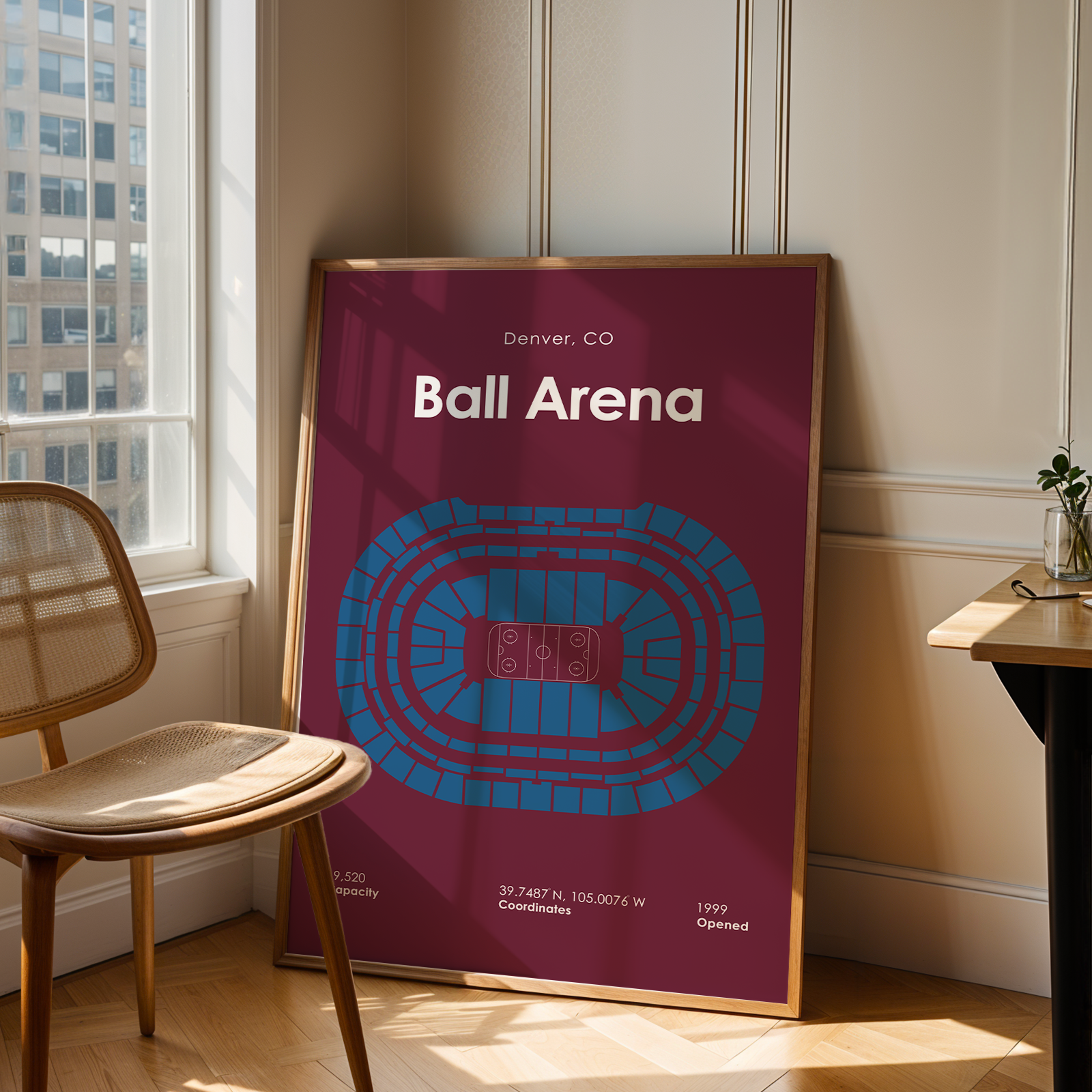 Framed poster of Ball Arena in Denver, CO on a wall next to a chair.