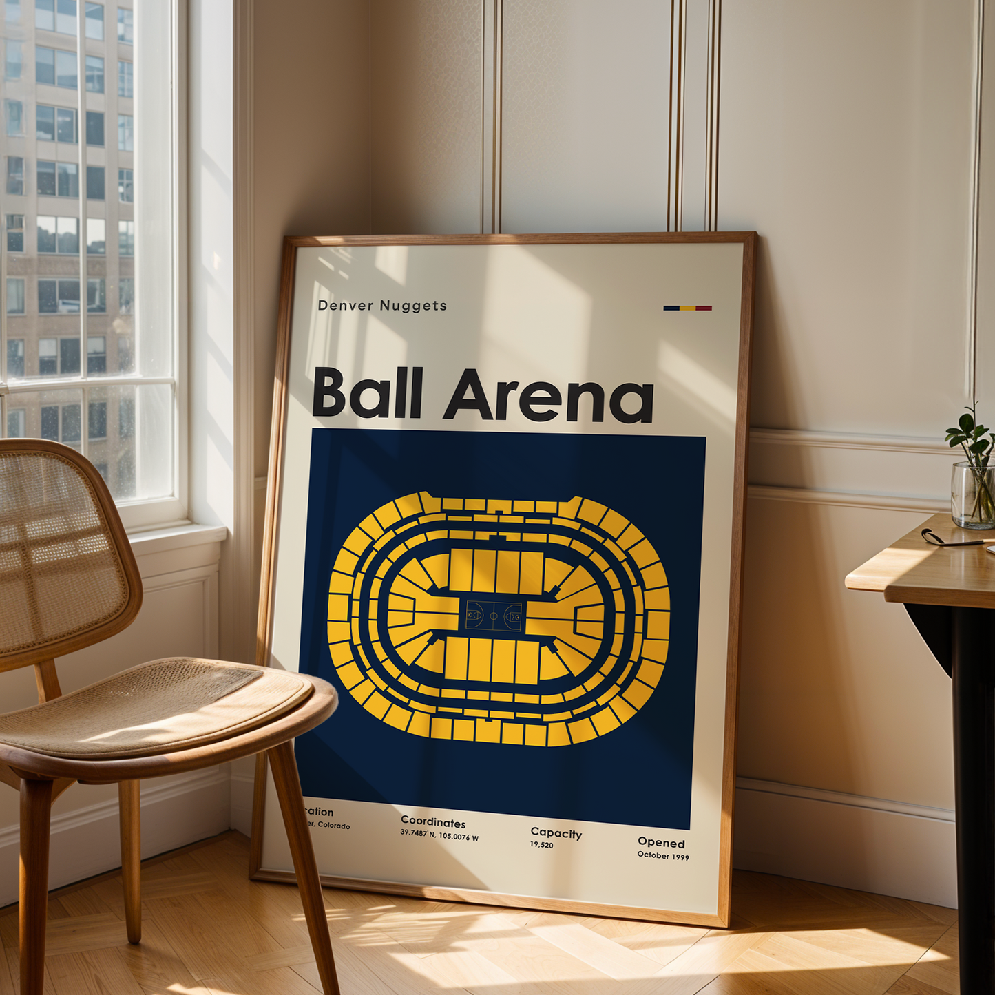 Framed poster of Ball Arena in a room with a chair and table.