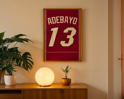 Framed jersey with 'Adebayo 13' on a wall above a wooden cabinet with decorative items.